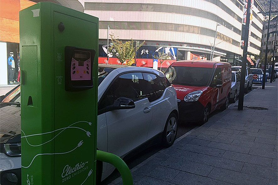 Un cotxe elèctric al costat d'un carregador.