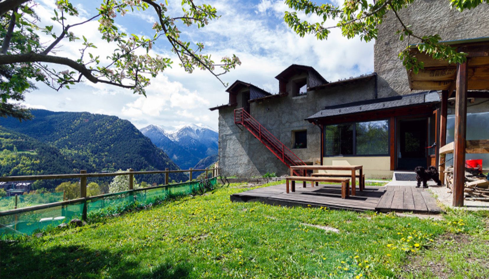 Una vista exterior de la Borda Jovell amb l'entorn enjardinat i les vistes que l'envolten.