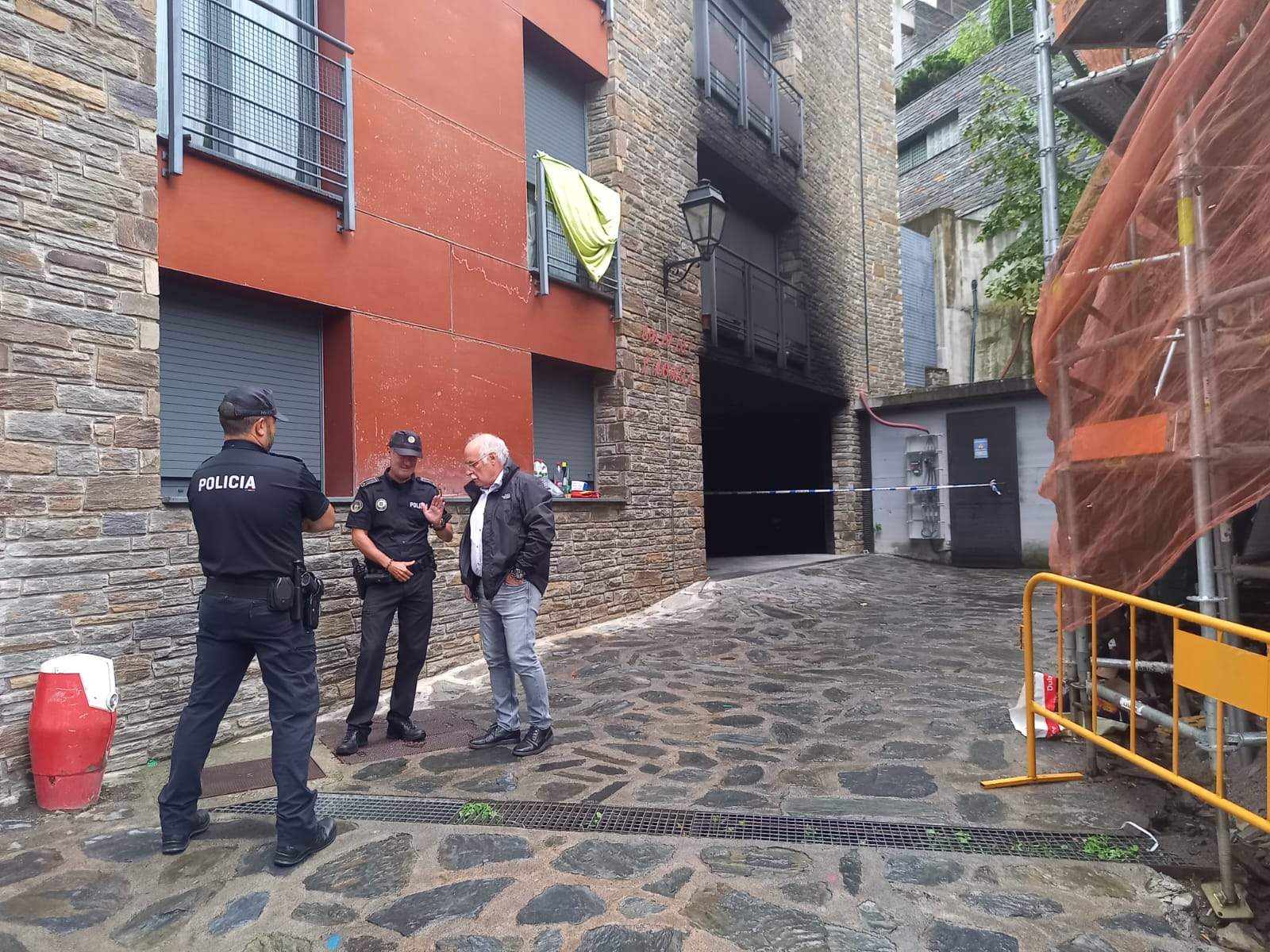 Dos policies que custodien l'edifici parlant amb el director general de Capesa, Eduard López, amb l'accés al pàrquing sinistrat al fons.