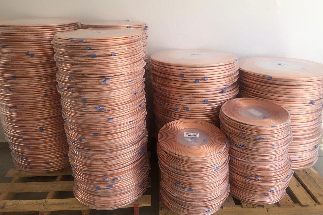 Rotlles de tub de coure apilats en una nau.