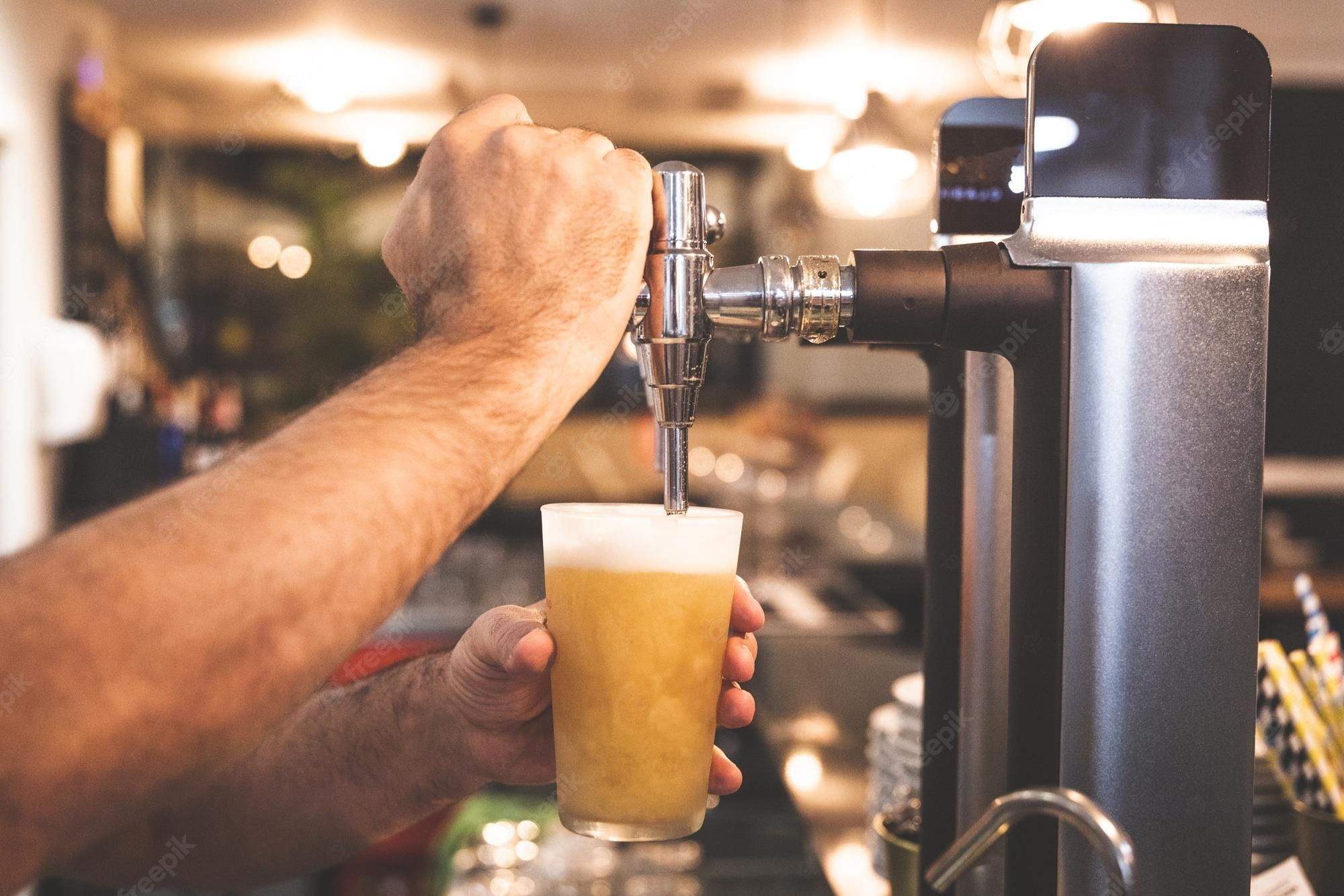 Un empleat d'un establiment de restauració preparant una cervesa.