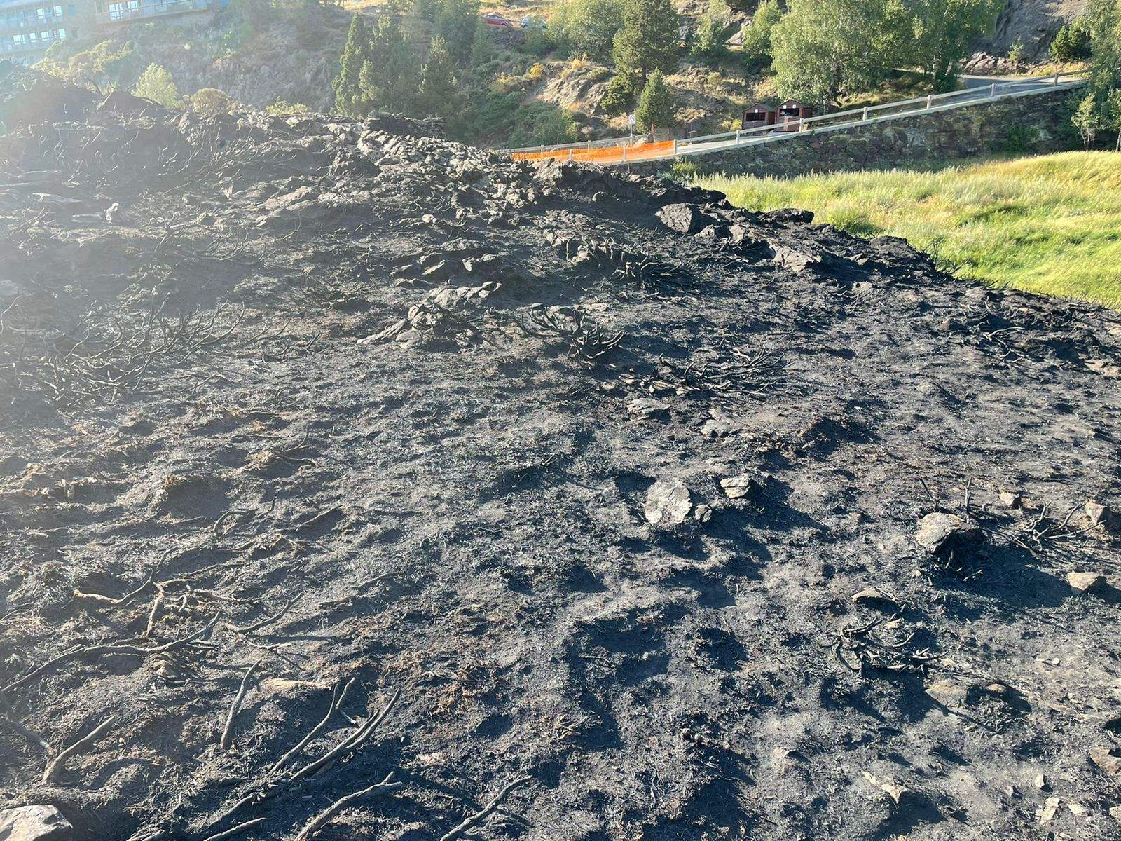 Part del terreny cremat en l'incendi amb la carretera i la zona on es treballava al fons.