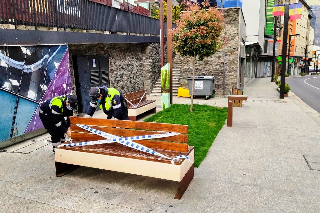 Dos agents comunals precinten un banc a Andorra la Vella  durant la pandèmia.