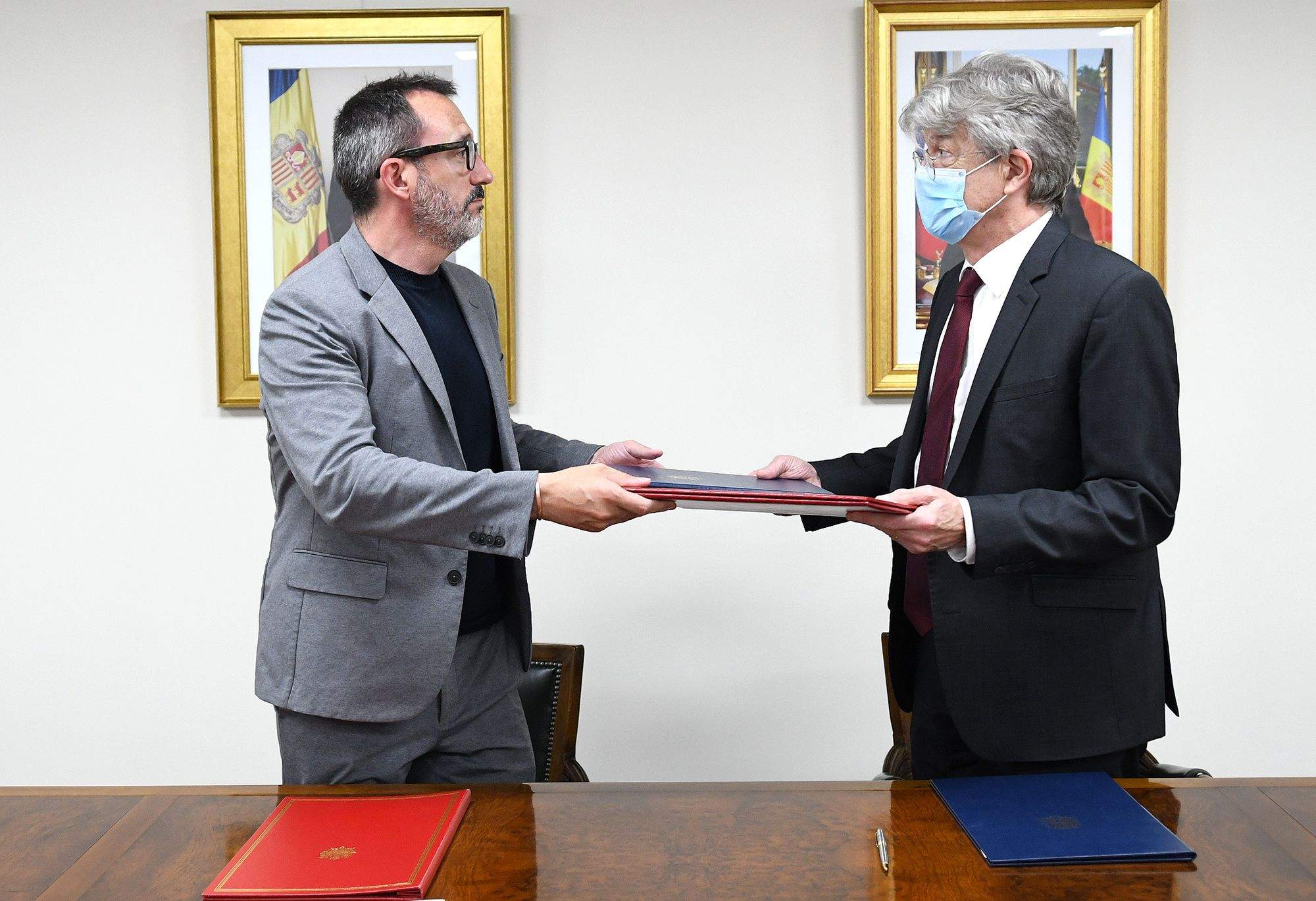 Filloy i Tribolet intercanvien les carpetes amb els convenis, en l'acte de signatura al juny.