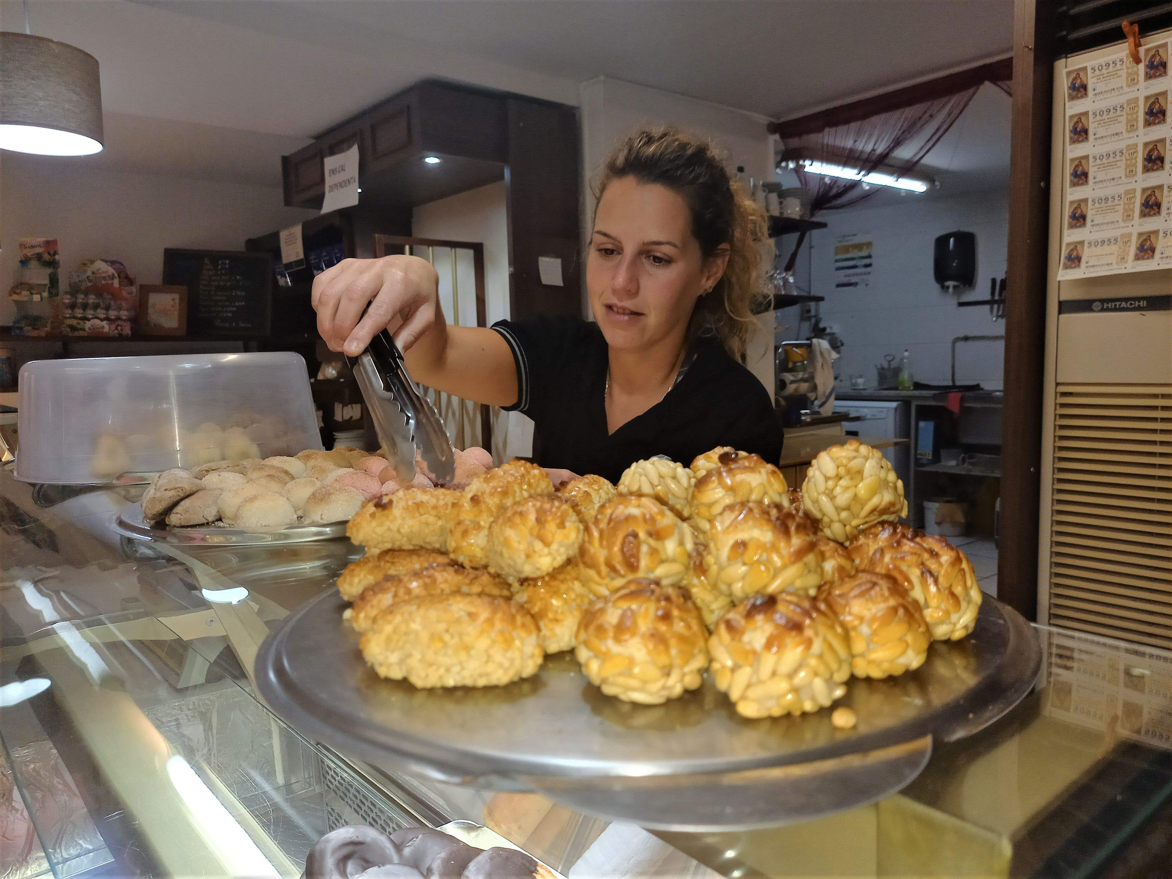 Una empleada d'una pastisseria prepara una comanda de panellets.