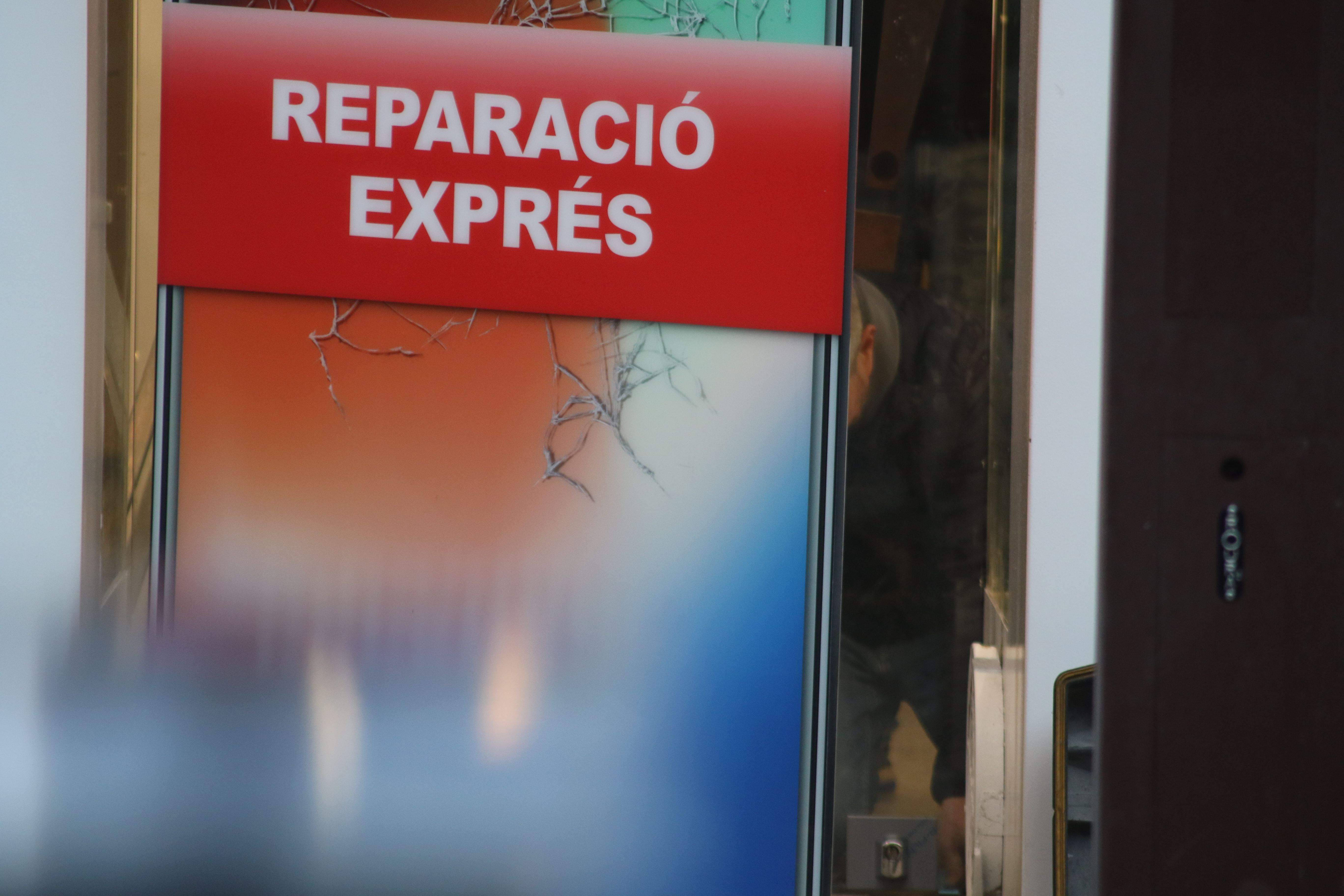 Un tècnic mirant de reparar el pany des de l'interior del local, aquesta tarda, amb la botiga inoperativa. La portaveu del Sindicat, Rebeca Bonache.