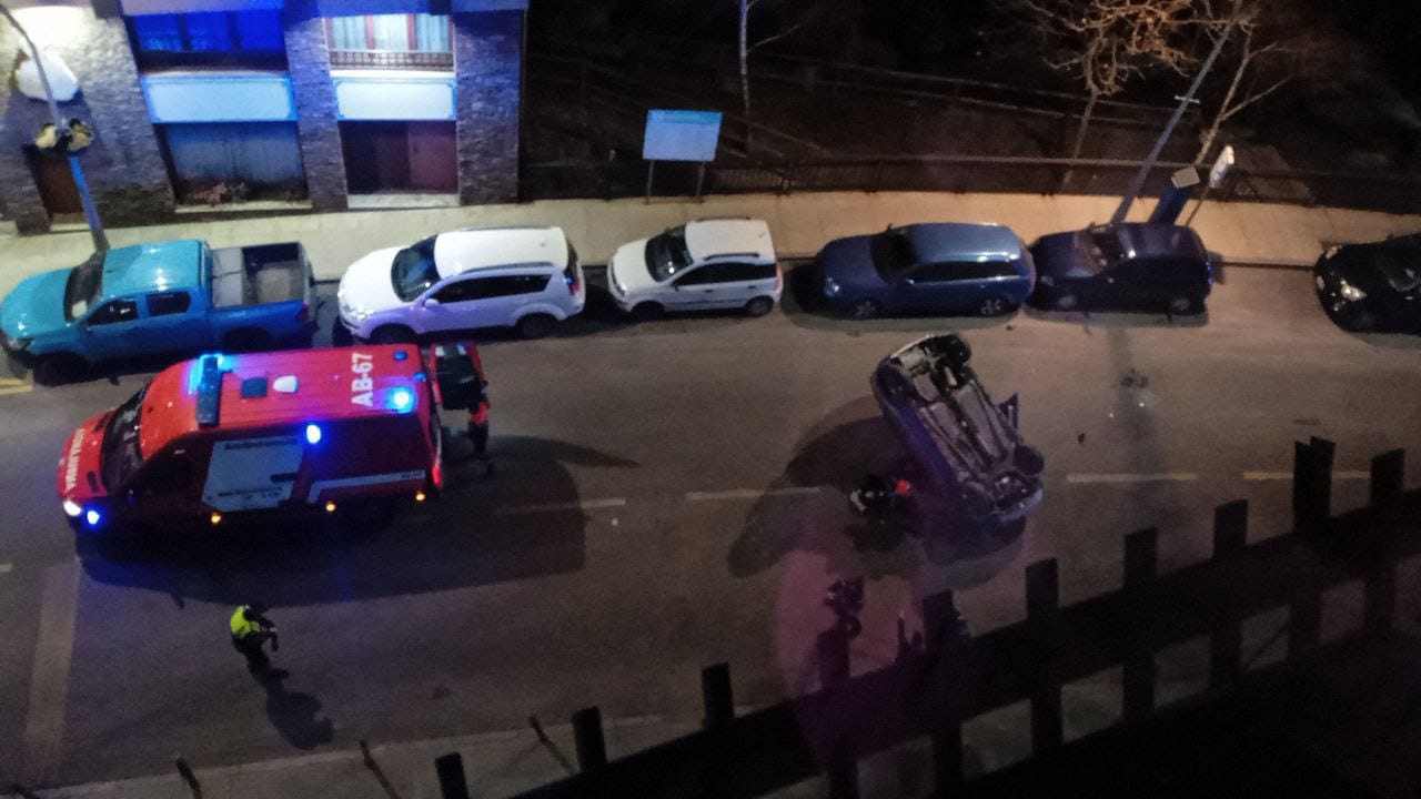 Els bombers al lloc de l'accident, amb el vehicle bolcat a uns metres.