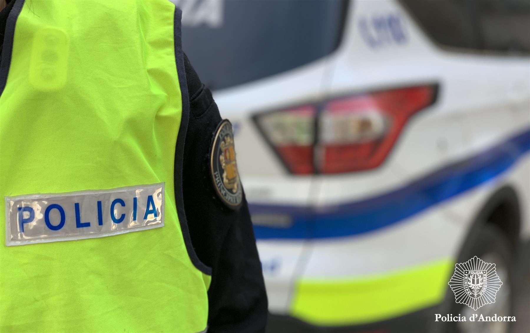 Un agent de policia al costat d'un vehicle policial.