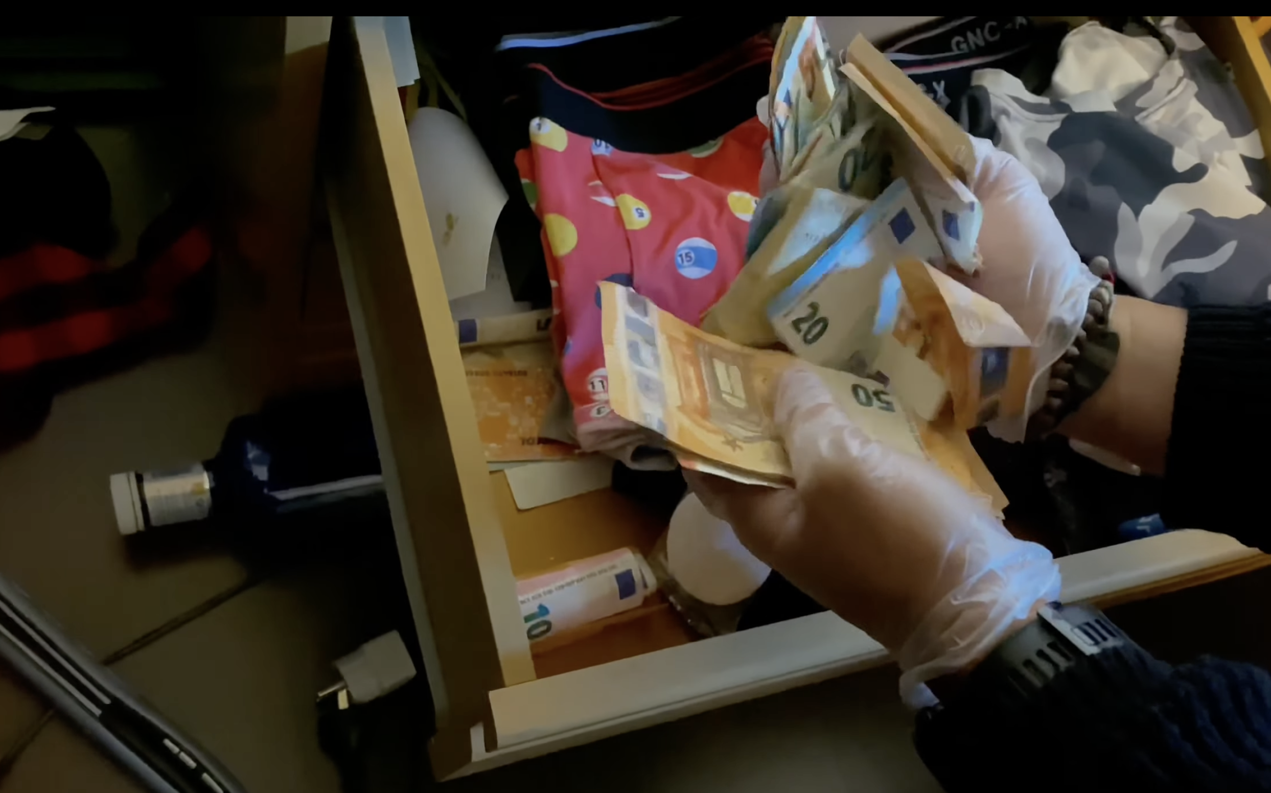 Un agent de policia recuperant diners d'un calaix del domicili de l'ara empresonat.