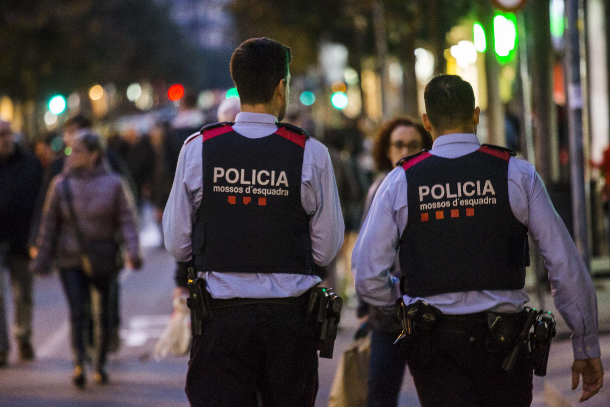 Dos agents dels mossos d'esquadra patrullant per carrers d'una ciutat catalana.