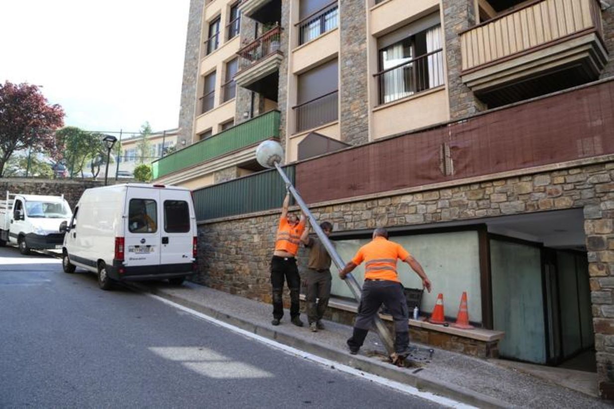 Operaris del comú instal·lant un fanal led a la voravia de Camp de Perot.