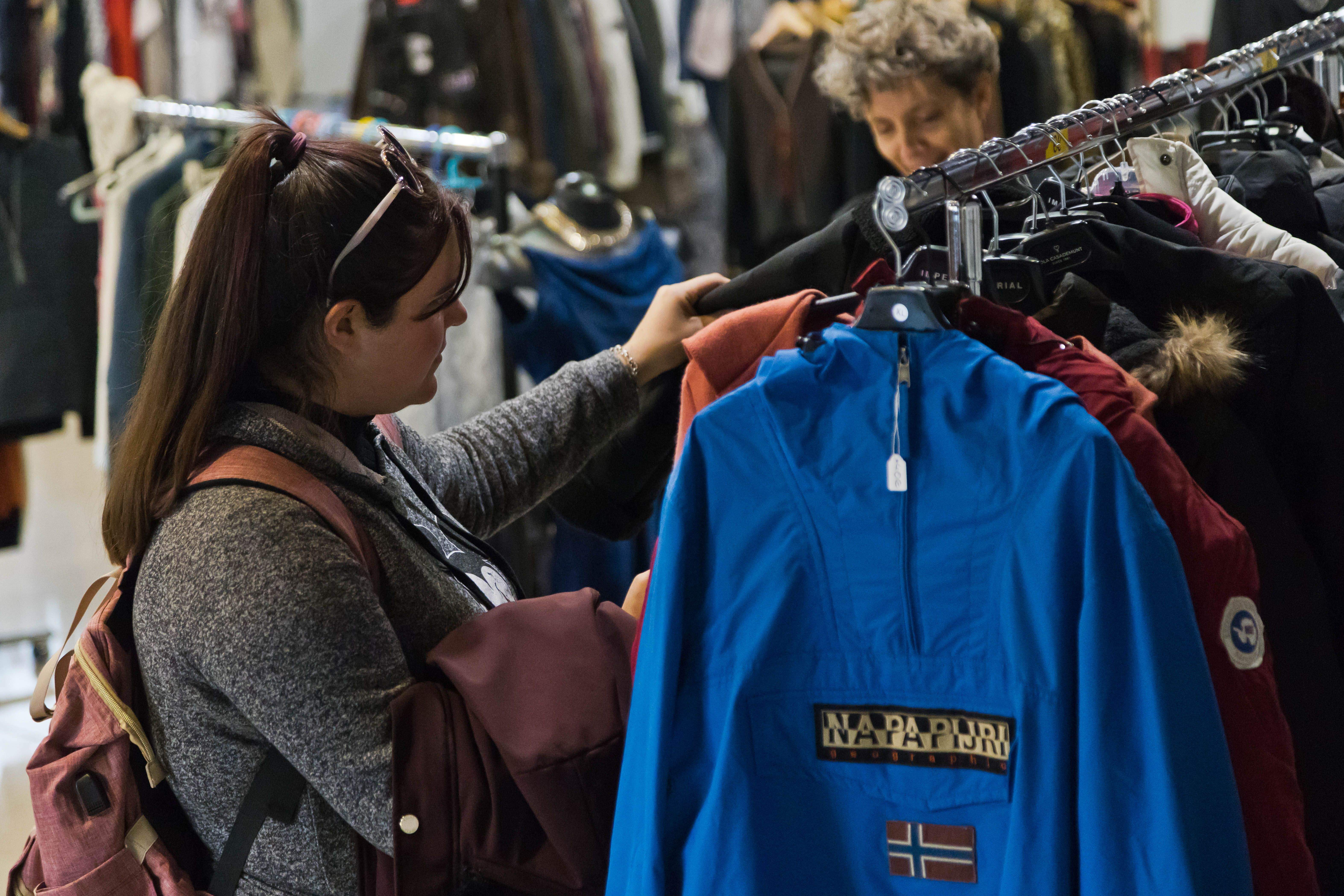Una potencial compradora mirant peces de vestir.