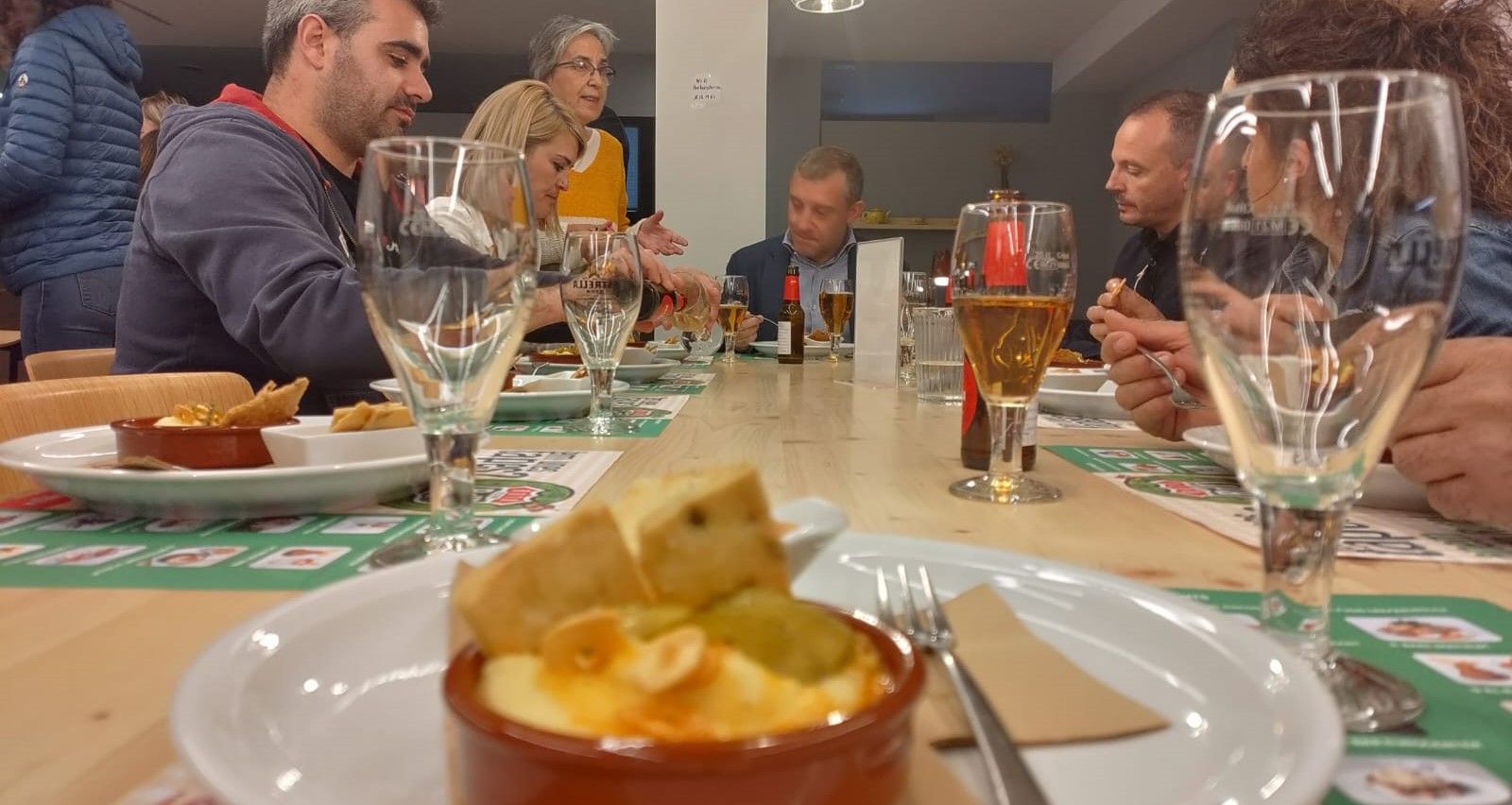 La restauradora Anna Porquet (dreta a l'esquerra de la imatge) explica al cònsol i als consellers el contingut de la seva tapa, la brandada Blanca Neus.