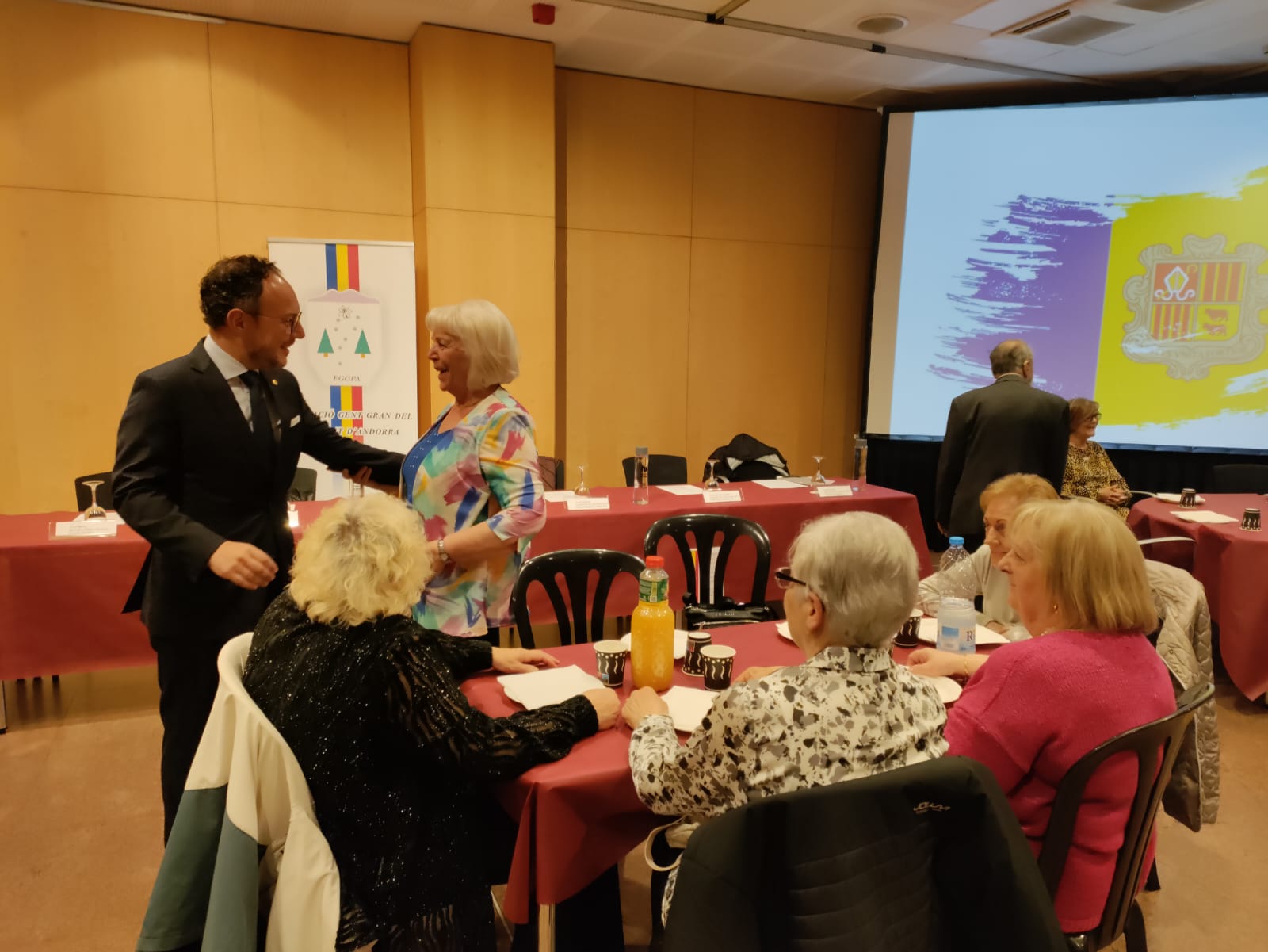 El cap de Govern, Xavier Espot saluda una assistent a l'assemblea.