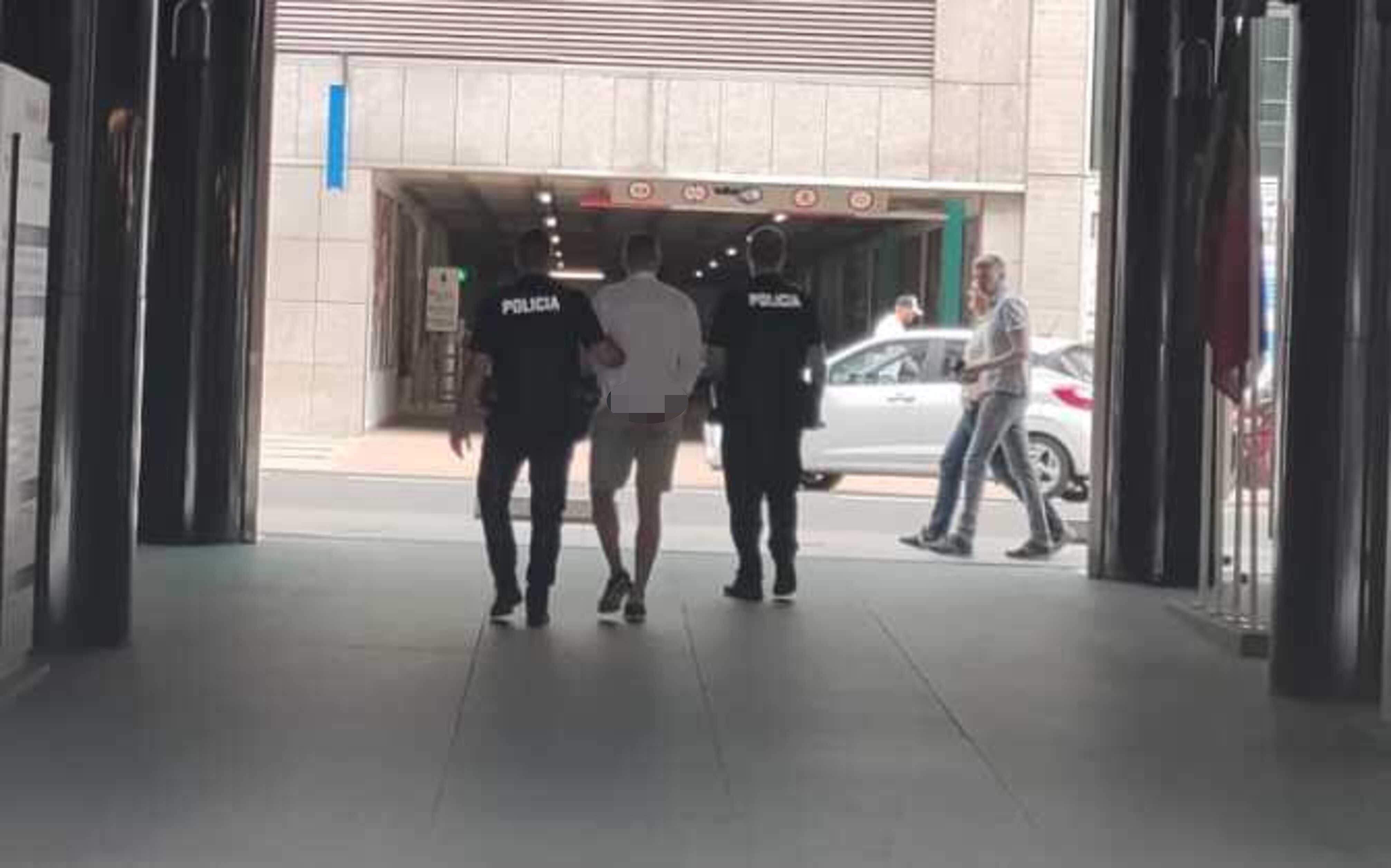 Dos agents de policia s'enduen detingut l'home.