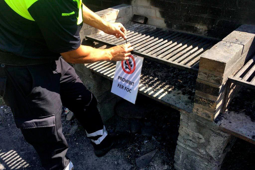Un agent comunal posant aquest divendres l'avís de prohibit fer foc en una barbacoa de la Comella.
