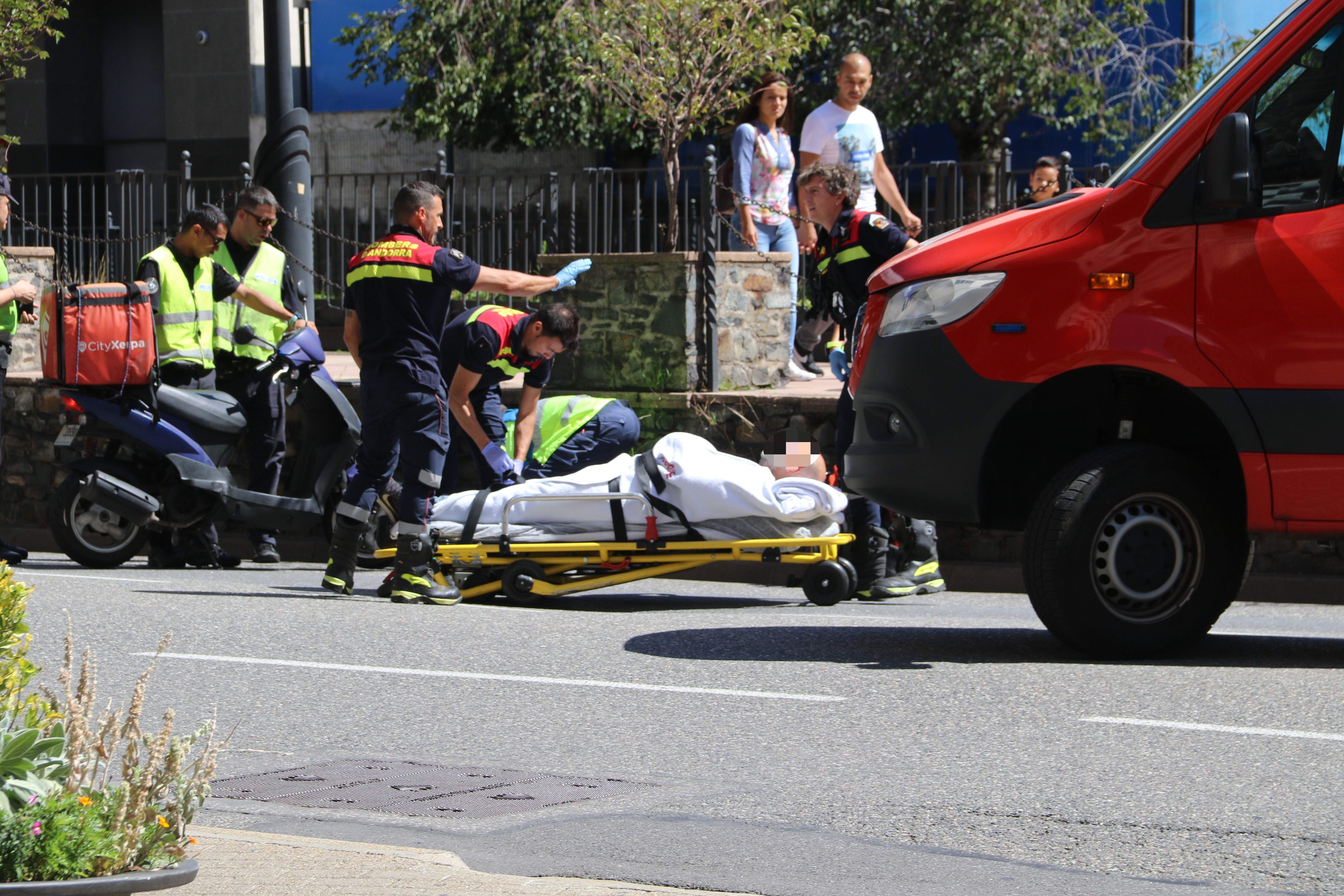 Els bombers s'enduen el ferit mentre policies es fan càrrec de la moto.