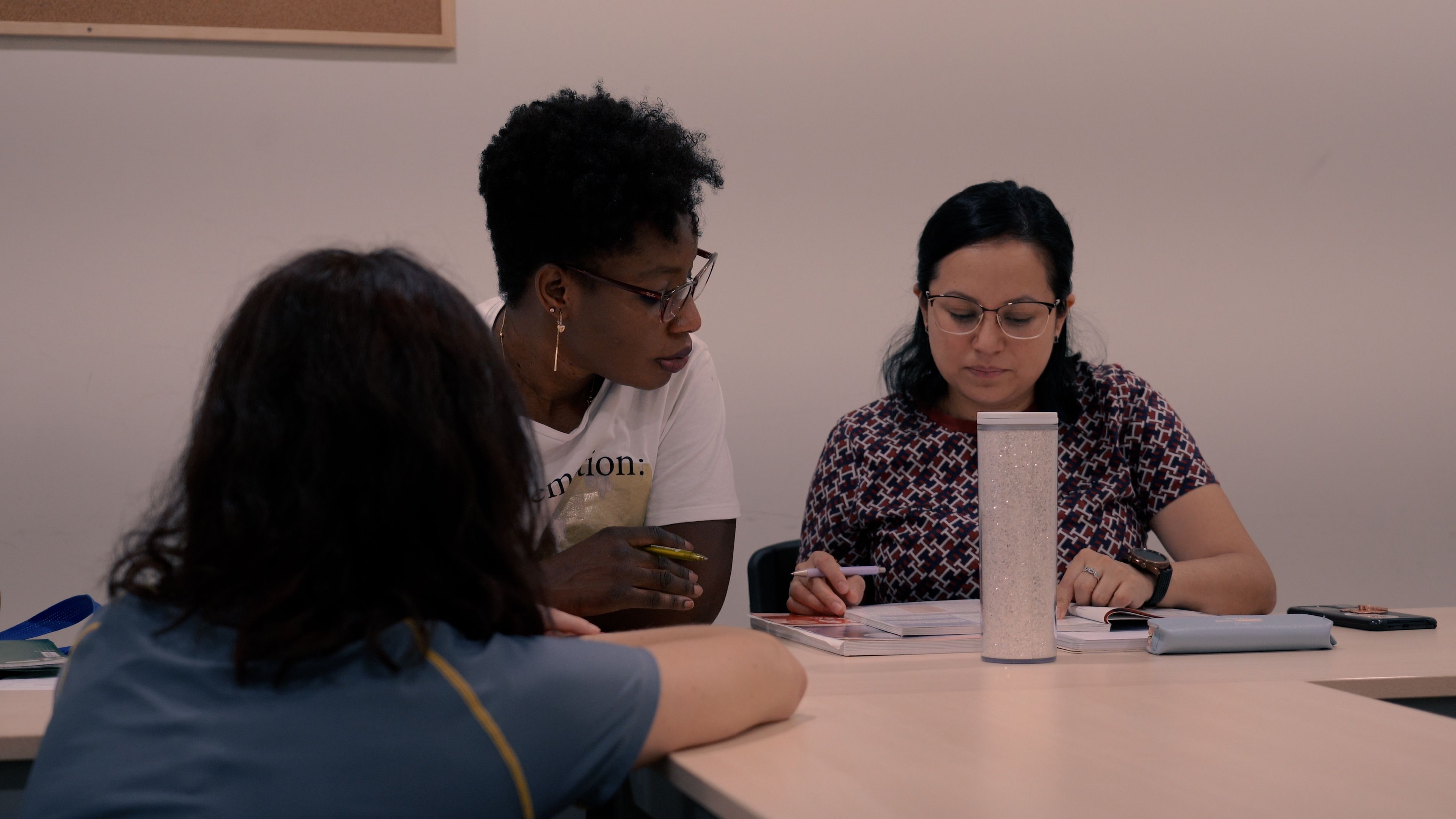 Dues alumnes amb la supervisió de la professora en una classe de català.