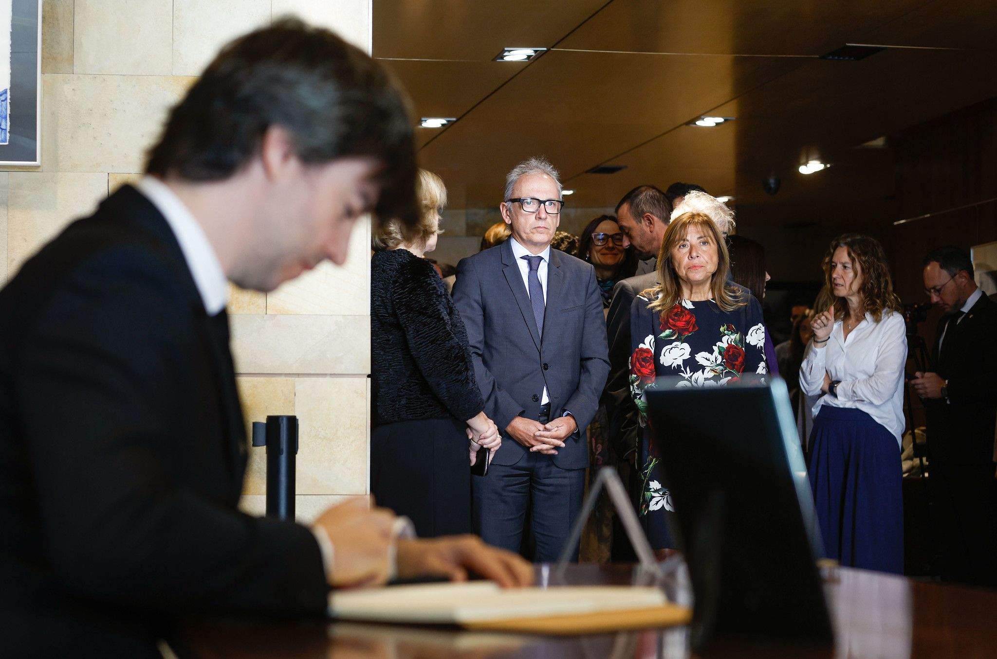 Ensenyat signant el llibre, amb ministres i altres autoritats esperan. La portaveu del Sindicat, Rebeca Bonache.
