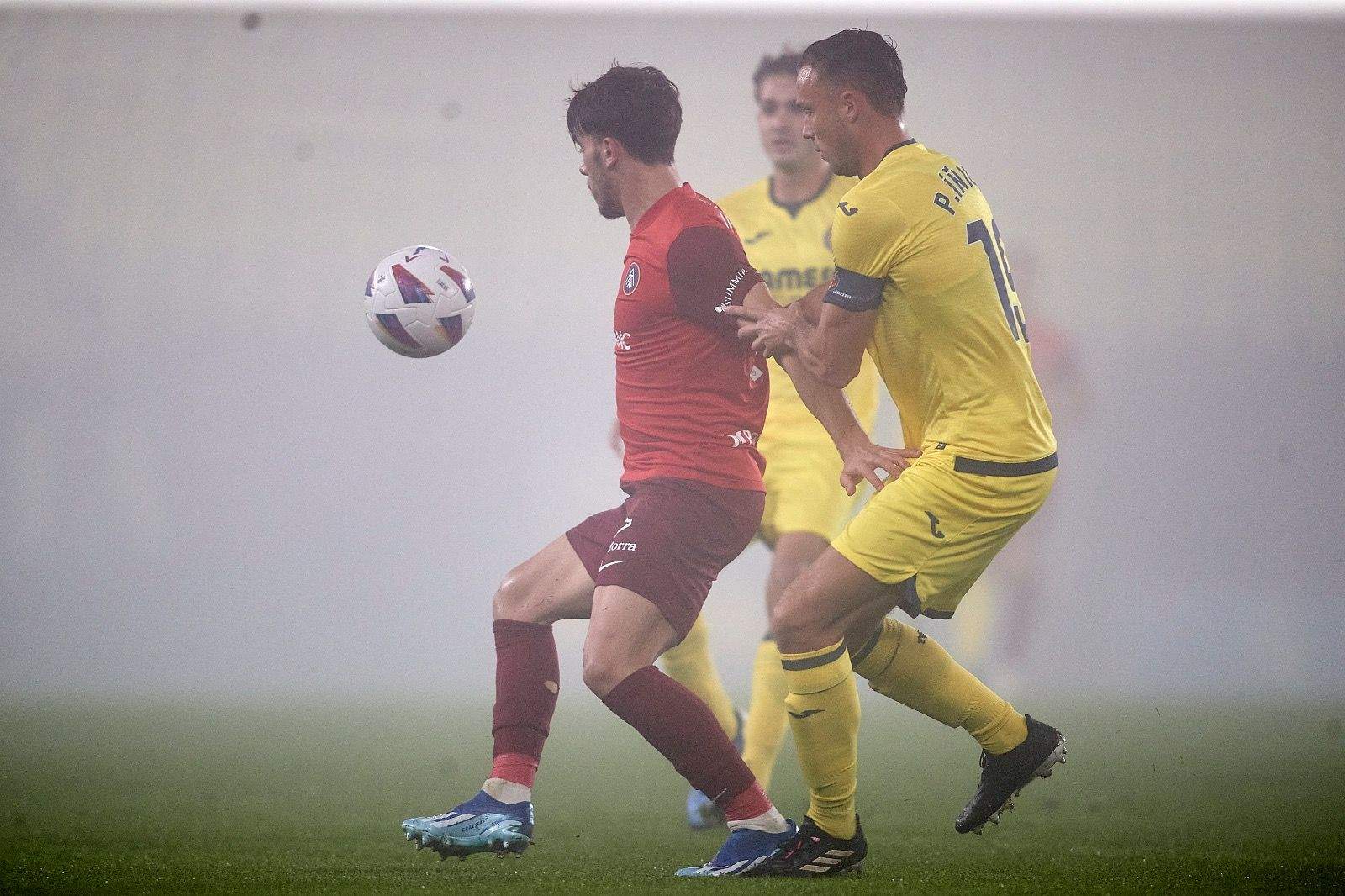 Un jugador tricolor intenta controlar una pilota davant la pressió de dos del Vila-real B.