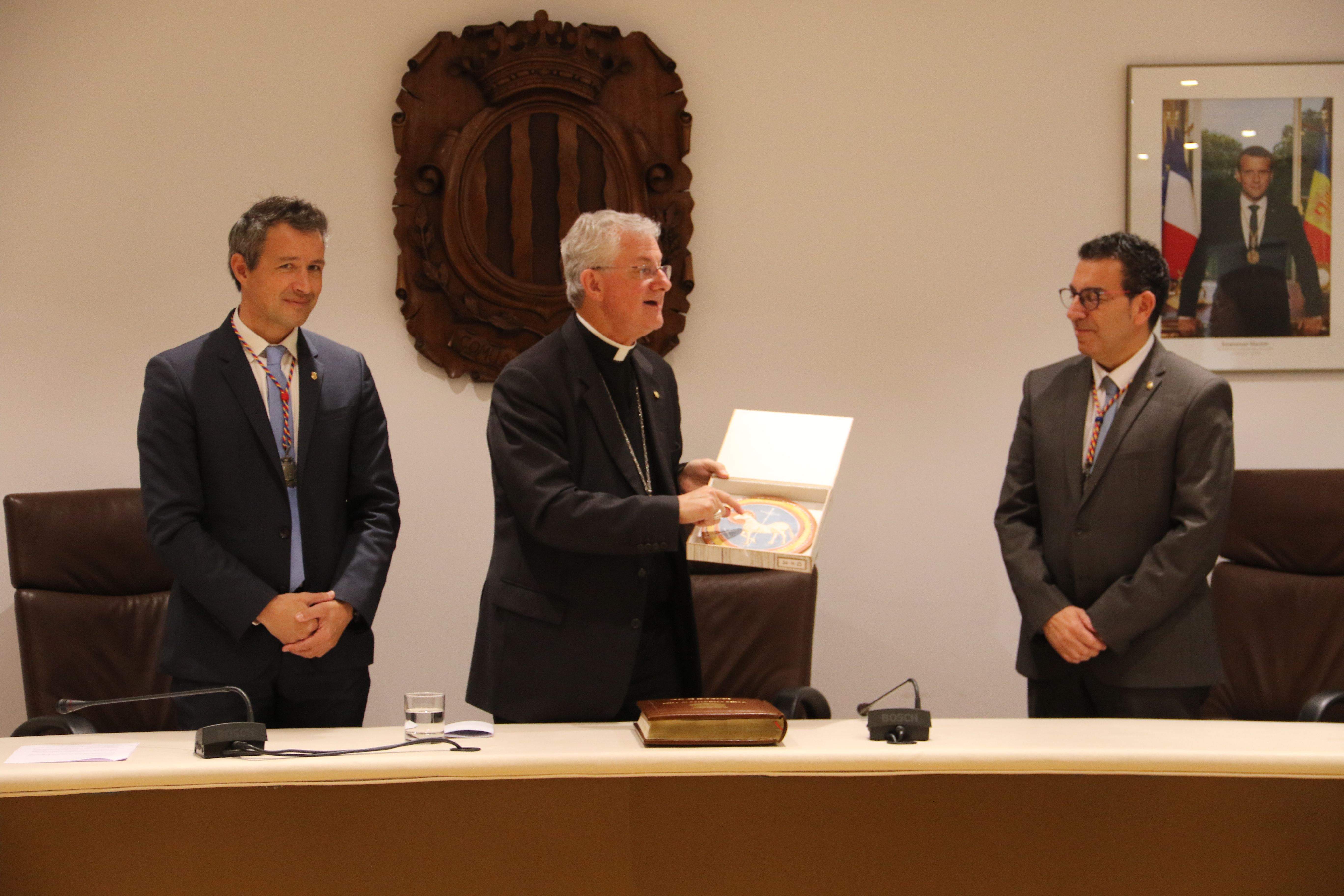 Joan-Enric Vives, entre David Astrié i Miquel Canturri, mostrant el record amb què el comú l'ha obsequiat.