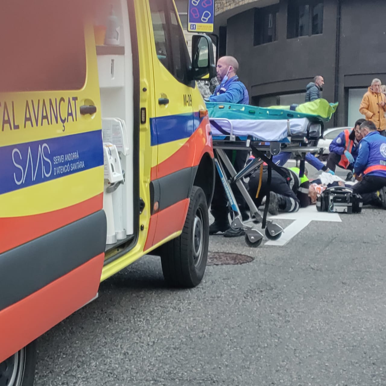 Sanitaris i un agent de circulació atenent la ferida al lloc de l'accident.