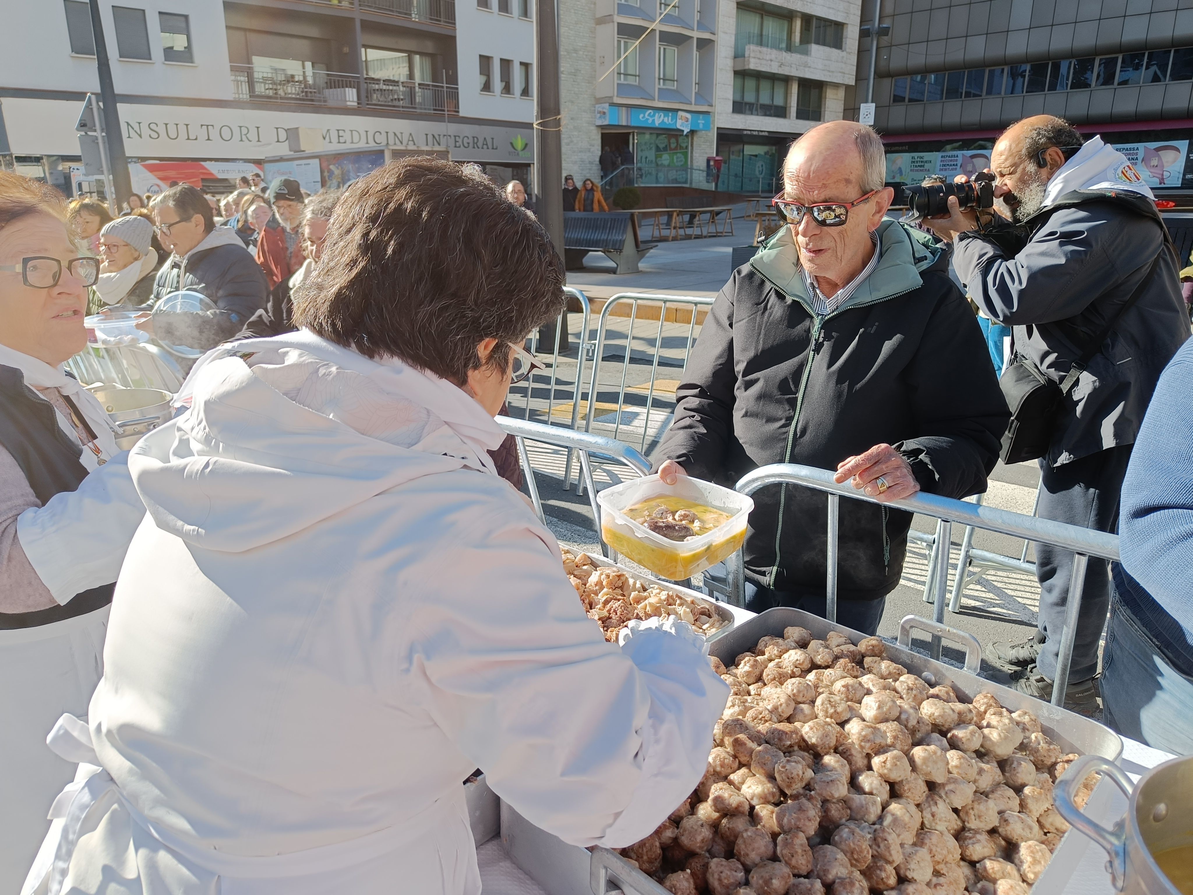 Ciutadans agafant la seva ració d'escudella.