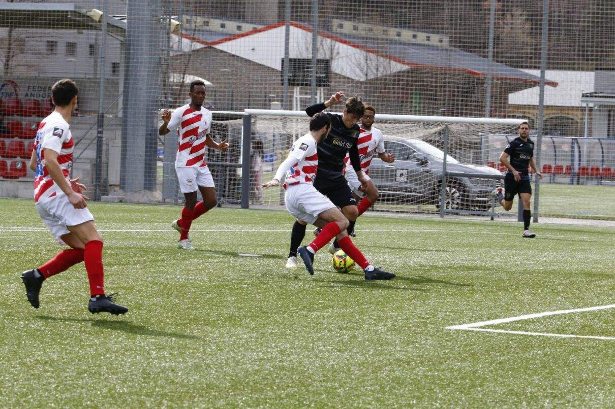 Els jugadors de l'Atlètic Amèrica, de blanc i vermell, proven de frenar un atac del FC Santa Coloma.