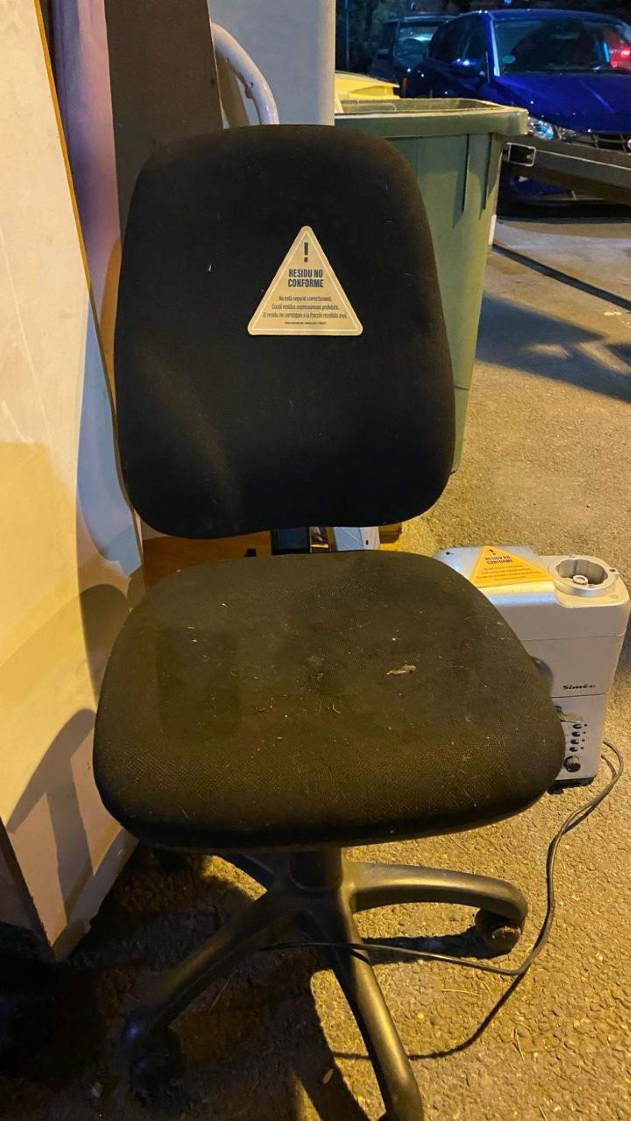 Una cadira a la via pública marcada amb l'adhesiu que informa que no s'ha seguit el procediment adequat.