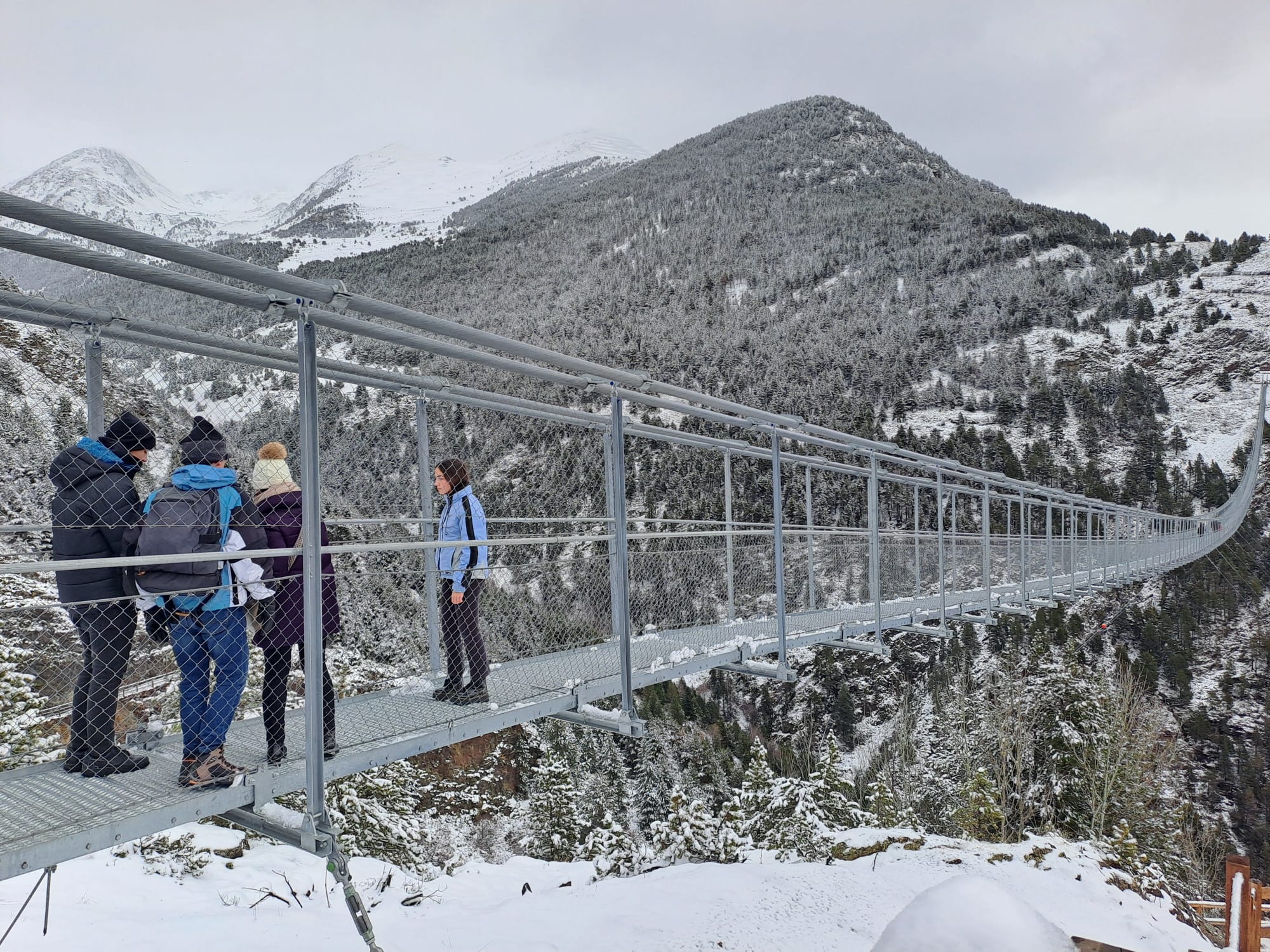 Quatre visitants a punt de travessar el pont tibetà.
