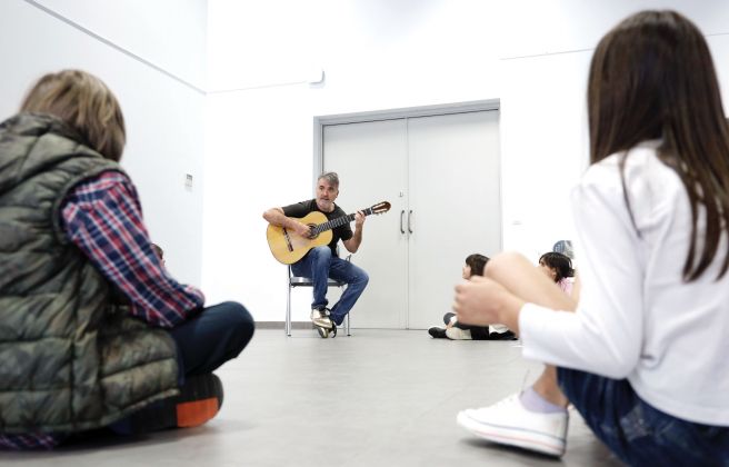 Rafael Serrallet amb la guitarra, davant l'atenta mirada dels més petits.