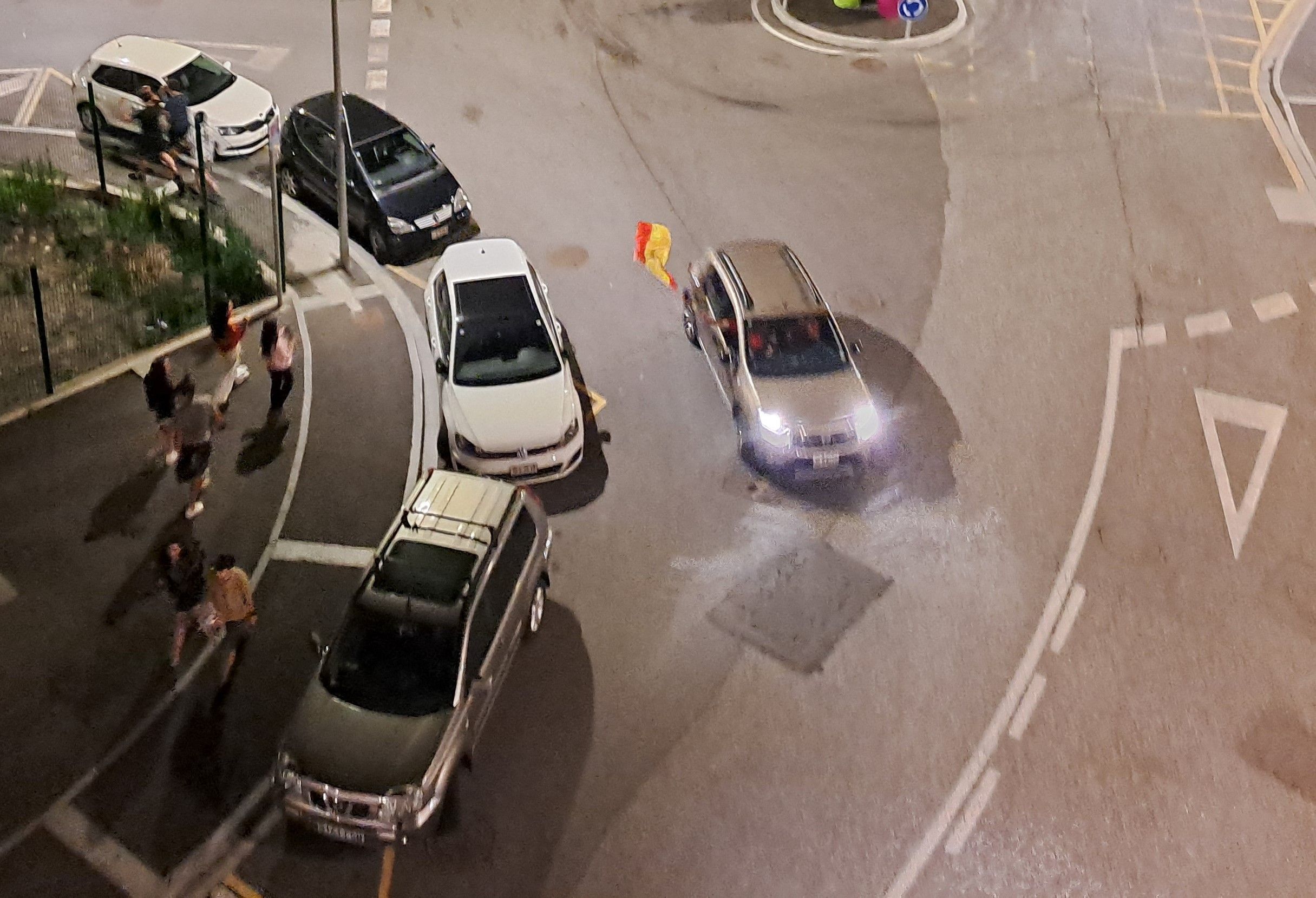 Un grup de joves salten al pas d'un cotxe amb la bandera espanyola a Encamp.