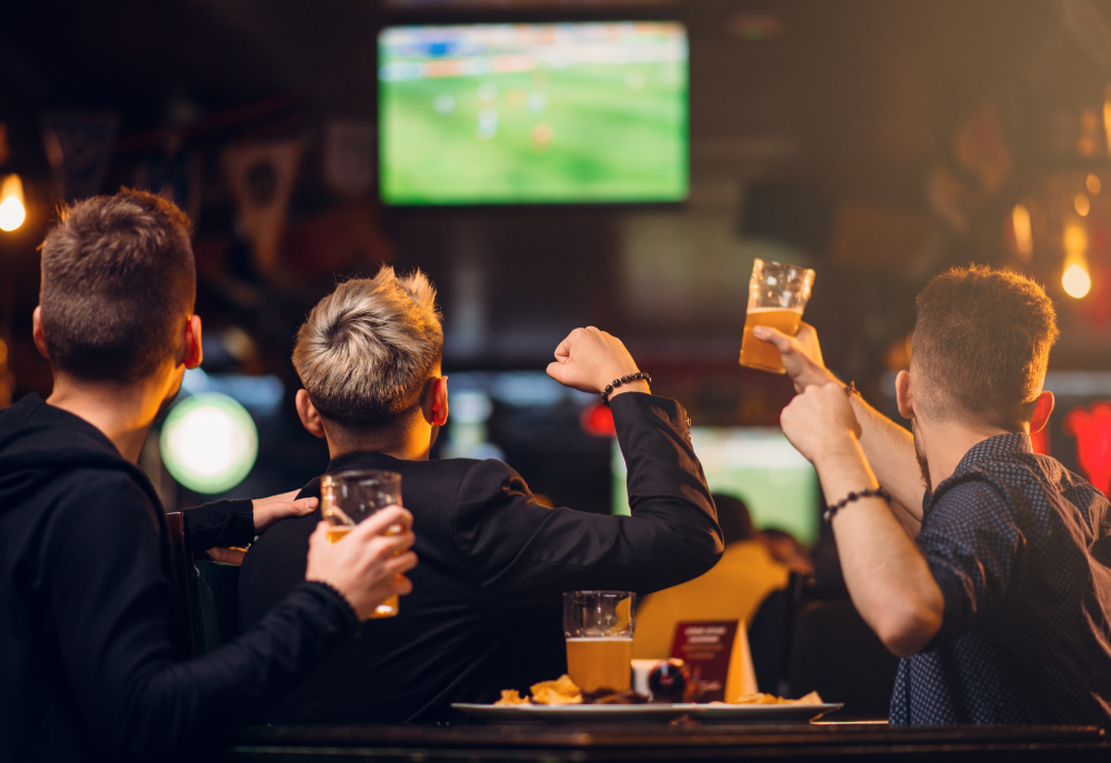 Uns joves veient futbol en un local de restauració.