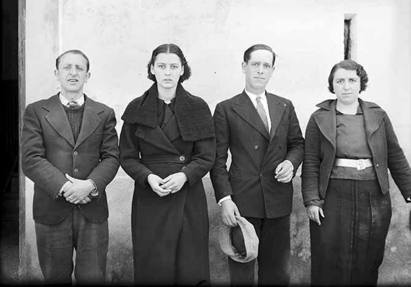 Retrat d’un grup de quatre refugiats de Lles (Cerdanya) a la façana de la casa Rebés a la plaça d’Andorra la Vella, fotografia feta al matí. D’esquerra a dreta: Pepito Sirvent Riart, al seu costat la seva dona Elvira Formentí de cal Fuster, Salvador Vidal Canal i la seva dona Montserrat Sirvent Riart,germana del primer home Tardor/hivern 1936