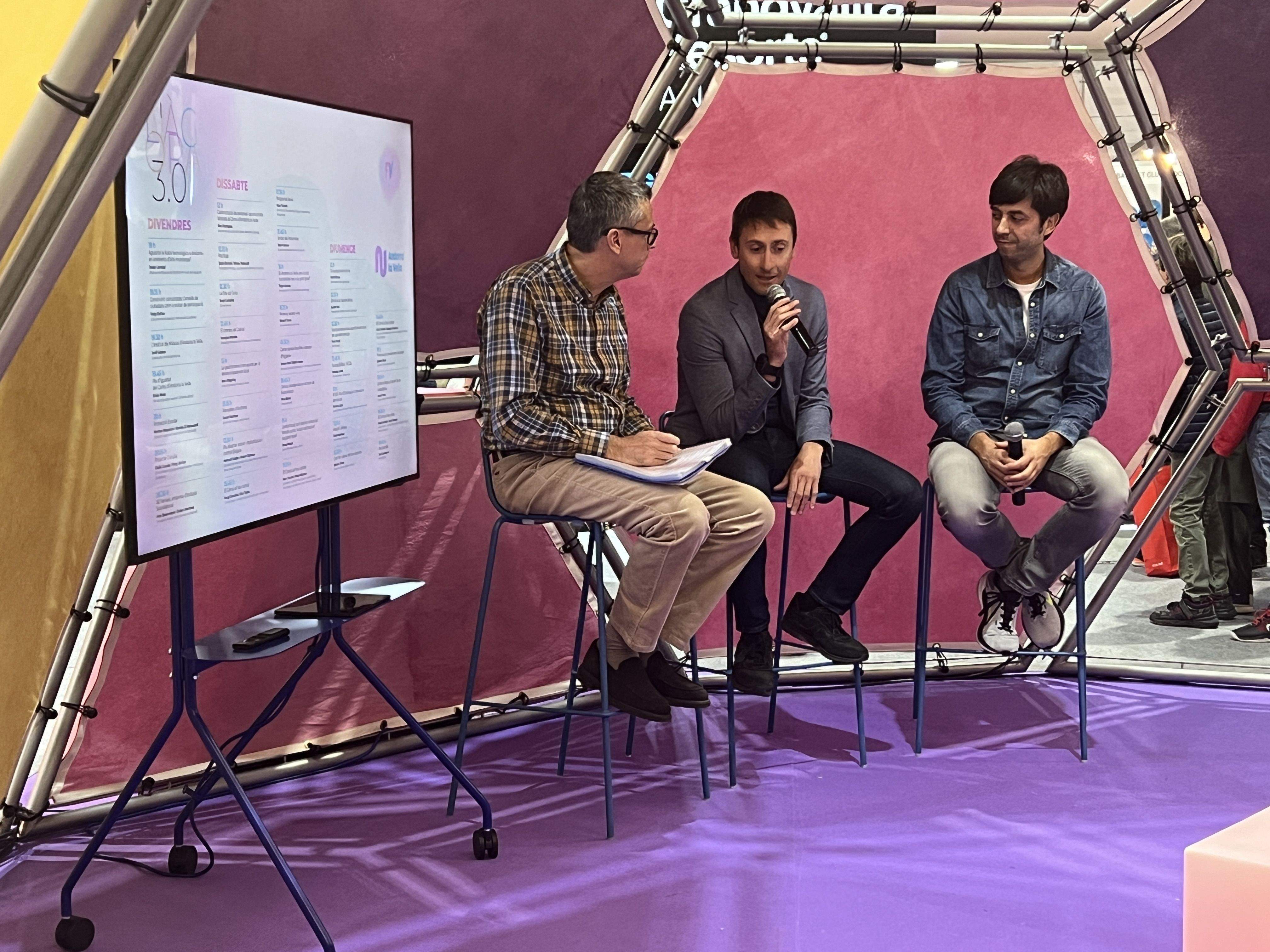 El cònsol, Sergi González (dreta), i el conseller Jordi Cabanes, amb el comunicador Xavier Albert en un acte a l'estand del comú aquest vespre.