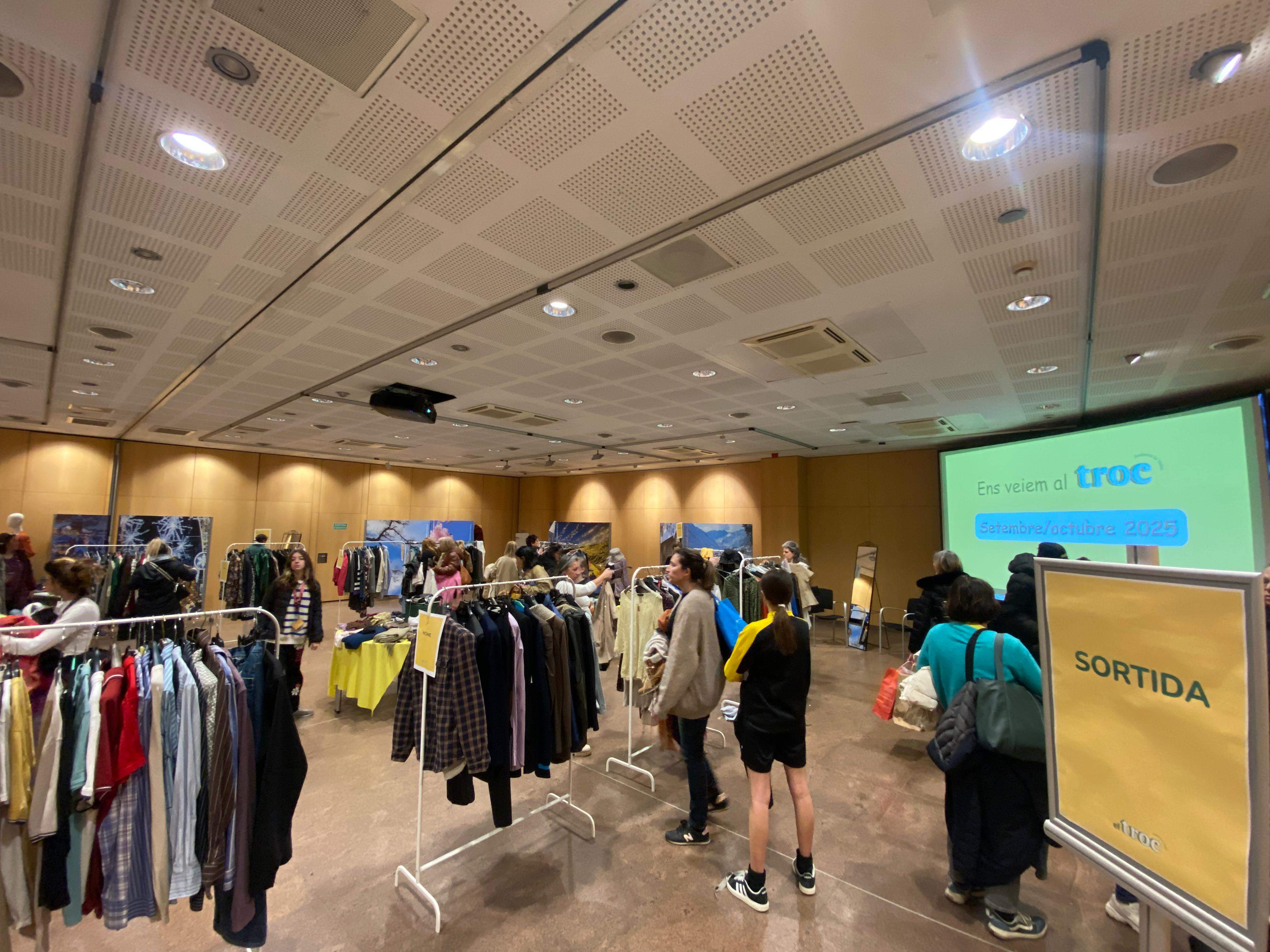 La roba exposada està col·locada en diversos penjadors distribuïts per la sala.