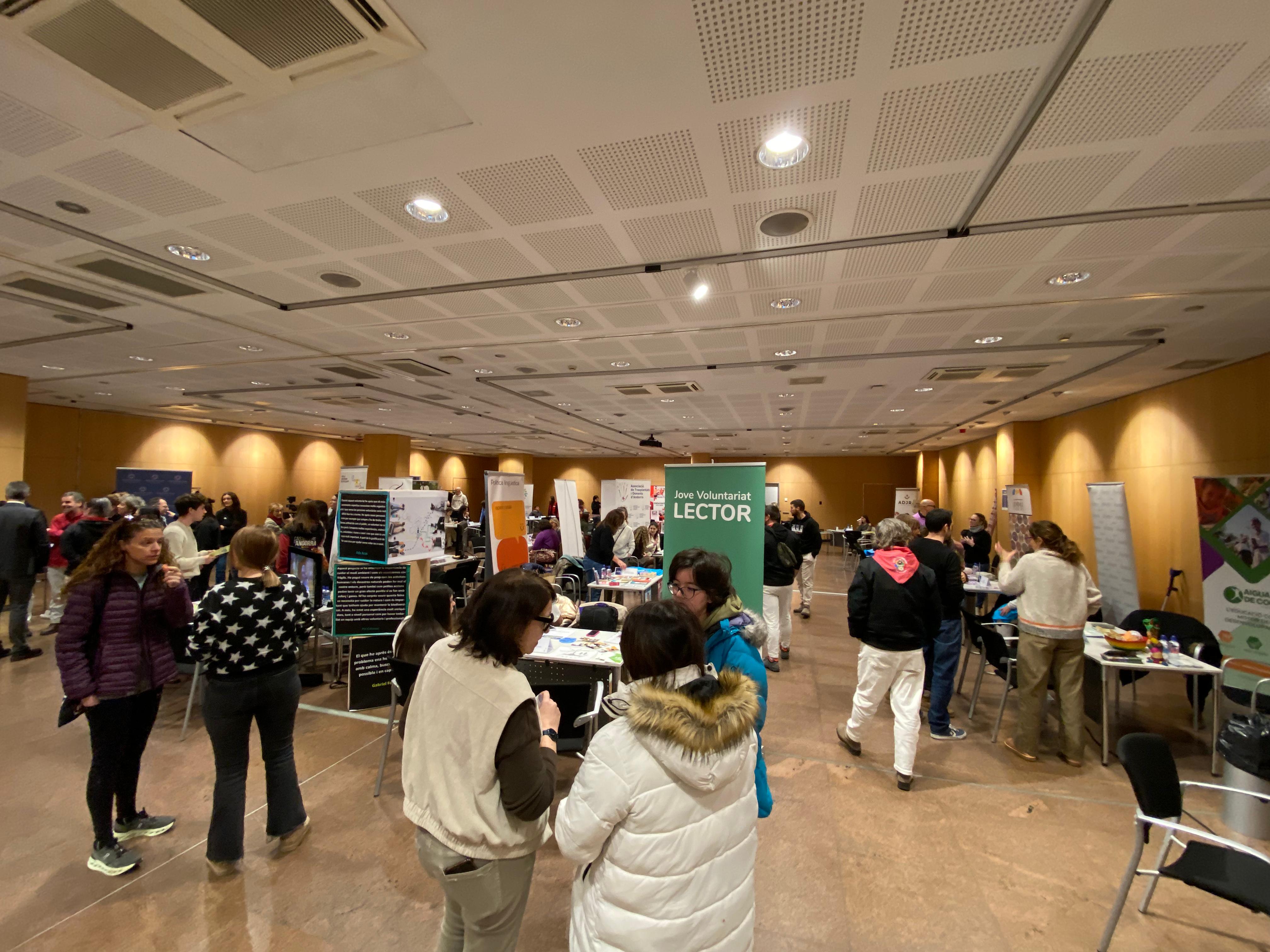 Diverses persones, conversant als estands de la sala.