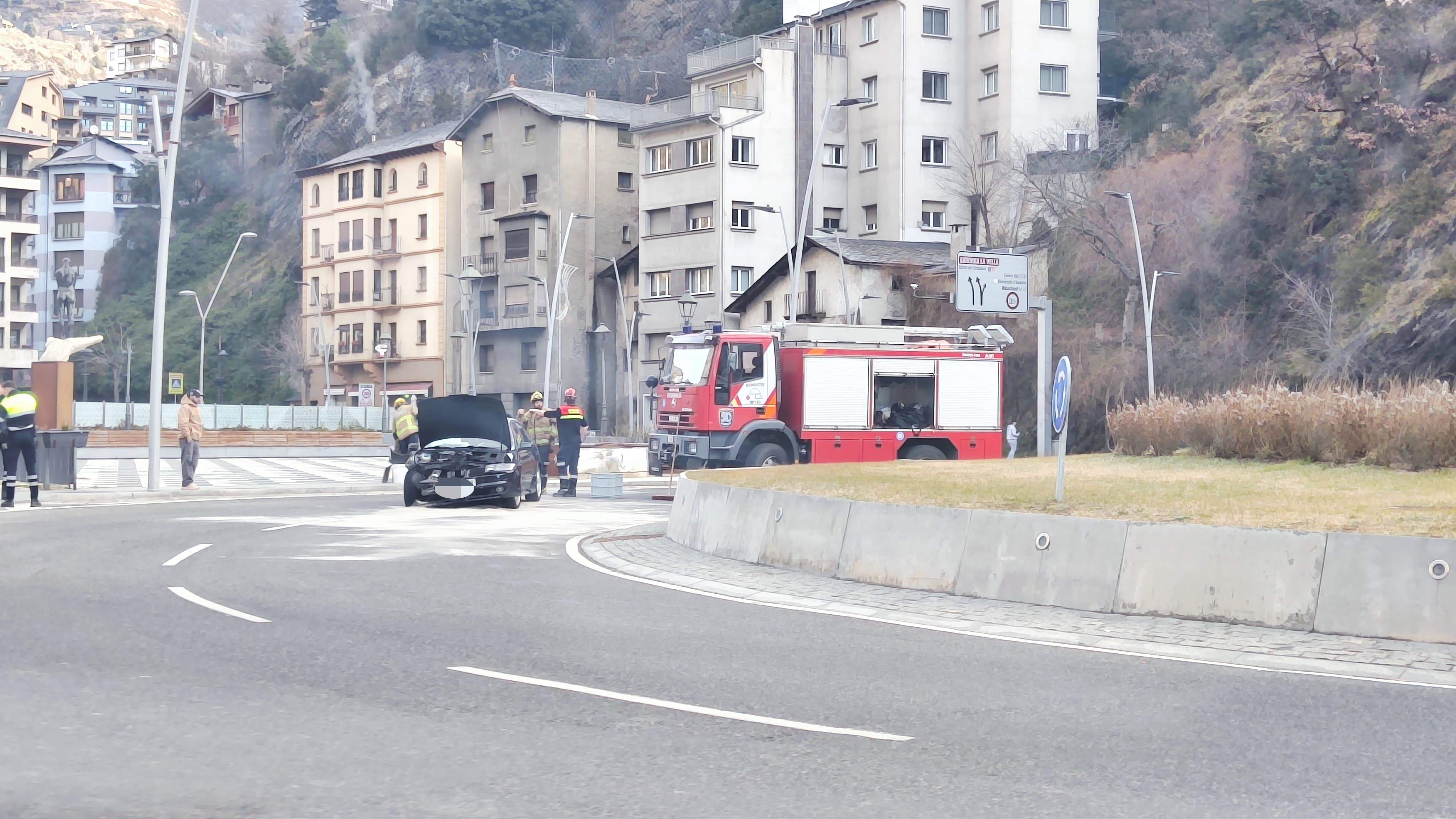 Els bombers netejant la calçada amb el cotxe encara al bell mig de la via.