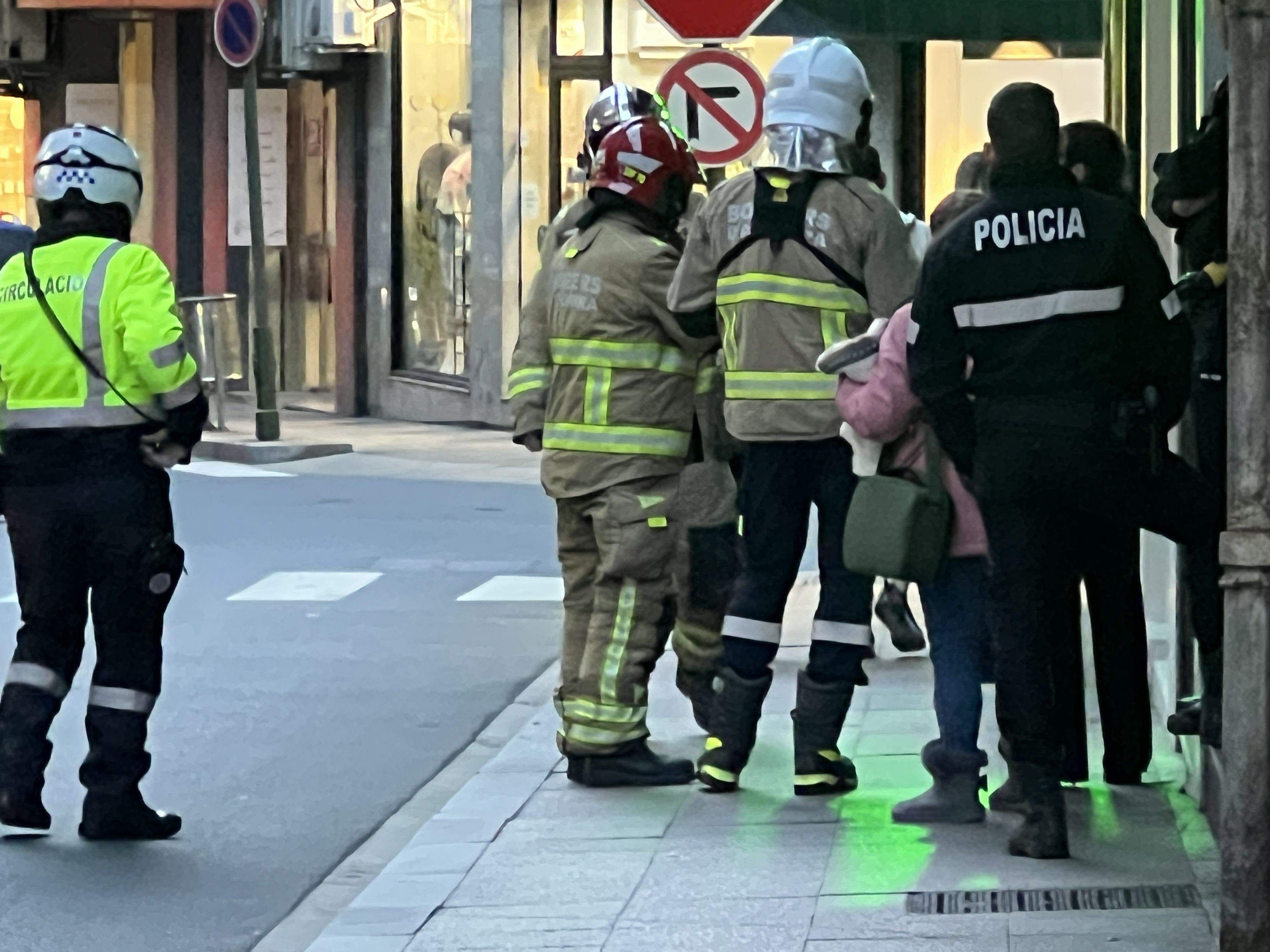 Bombers, policies, veïns i un agent de circulació a l'entrada de l'edifici.