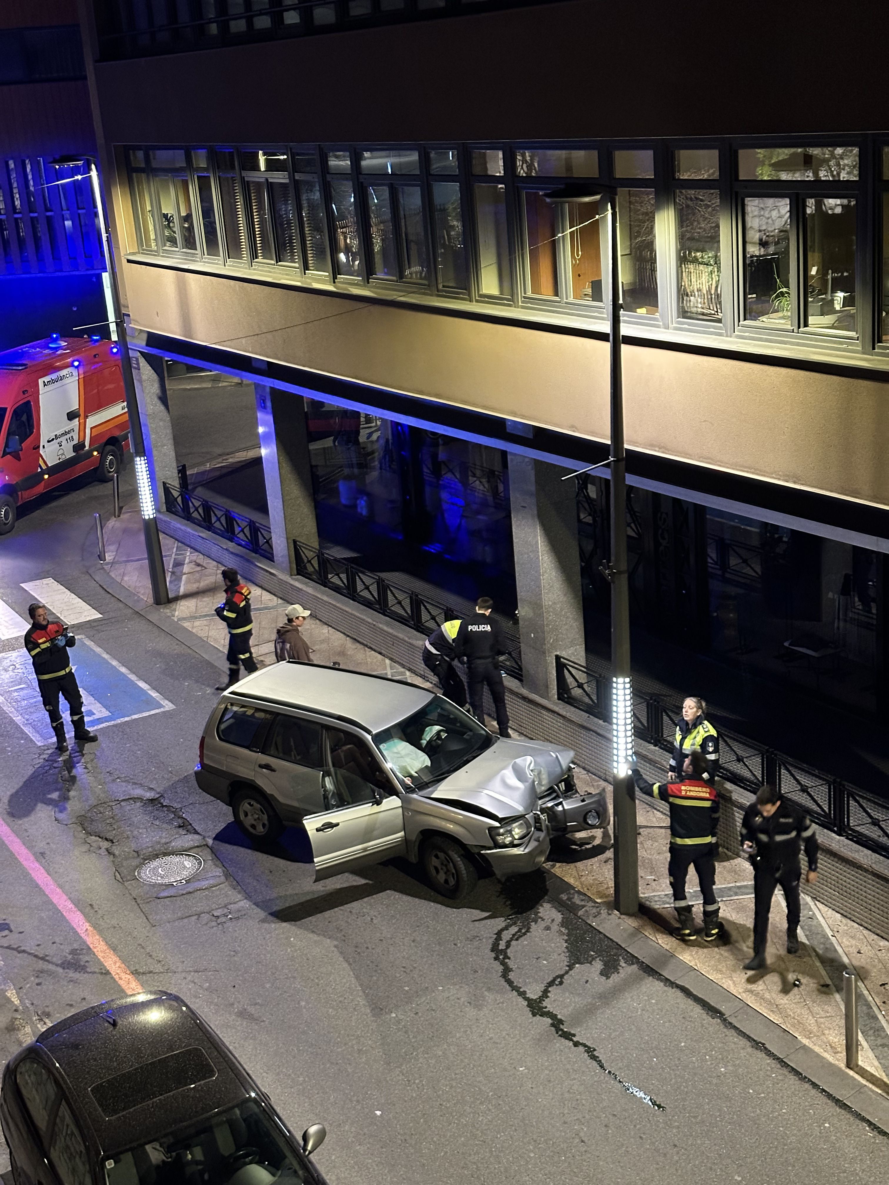 Bombers, agents de circulació i policies en el lloc dels fets amb el cotxe just després d'encastar-se contra el fanal.
