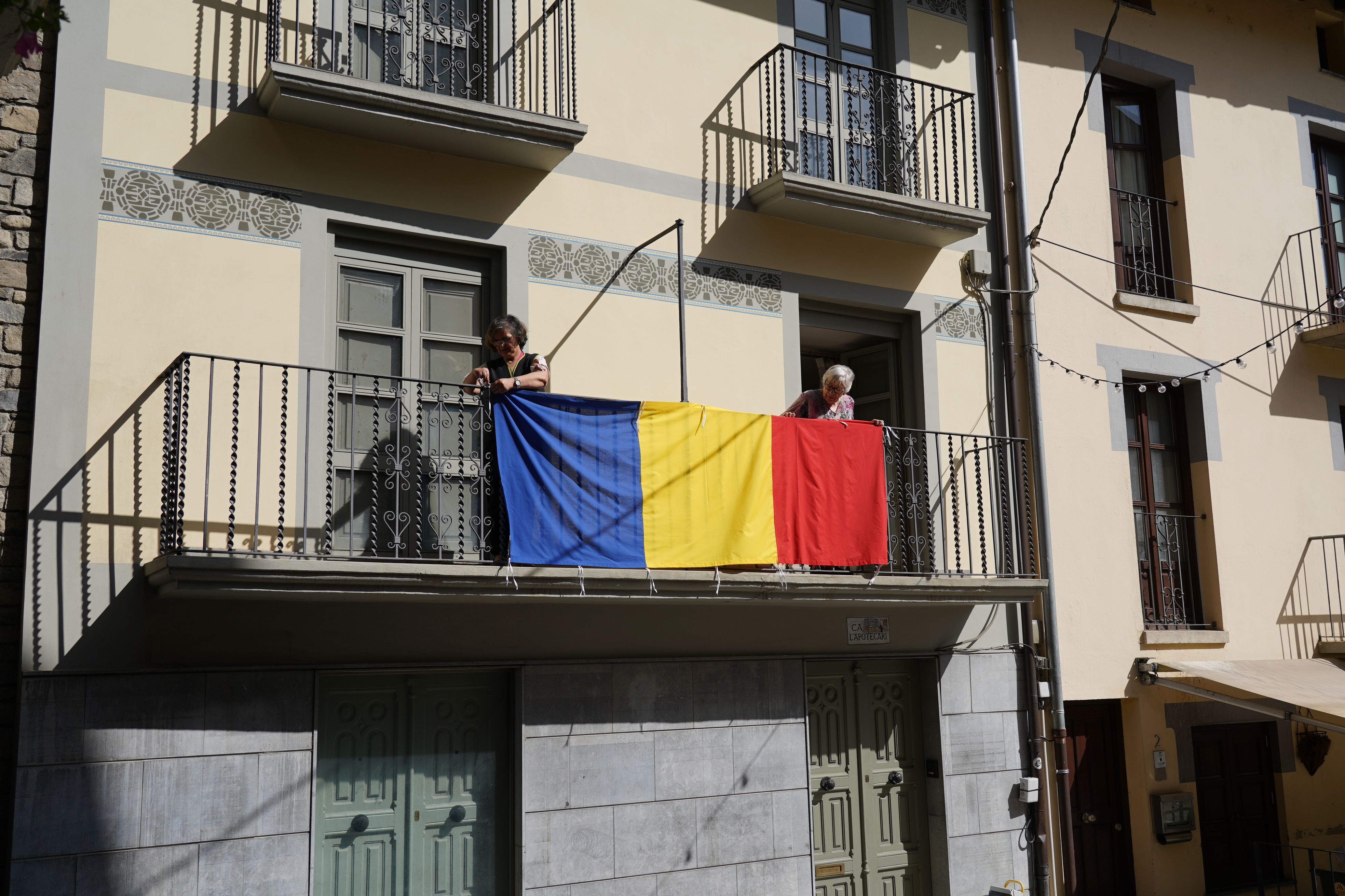 Dues veïnes del centre històric guarneixen el balcó amb la bandera andorrana. Dues veïnes del centre històric guarneixen el balcó amb la bandera andorrana.
