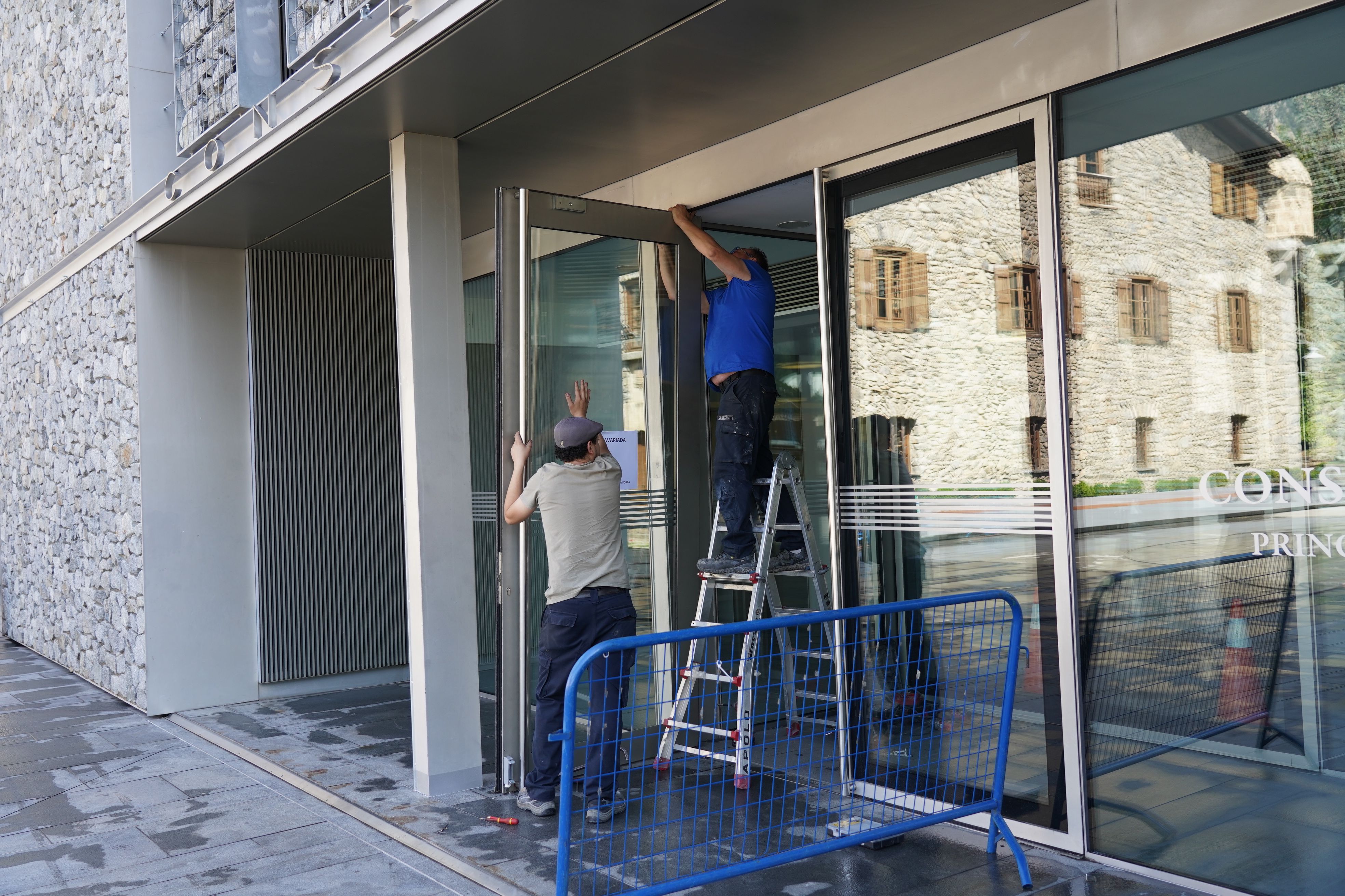 Dos operaris reparen la porta malmesa del Consell. Dos operaris reparen la porta malmesa del Consell.
