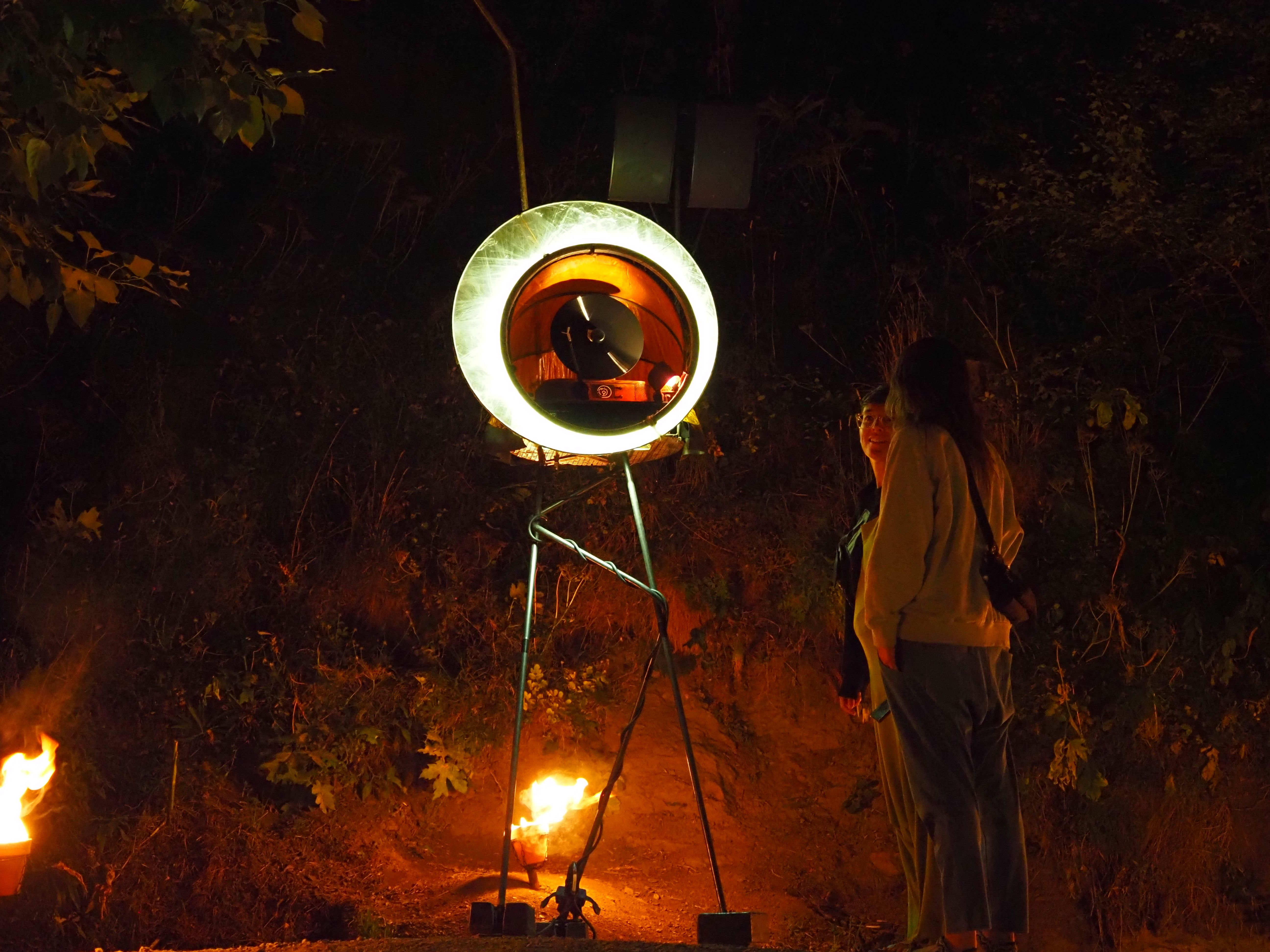 Dues persones contemplant una de les peces de la instal·lació de foc. Dues persones contemplant una de les peces de la instal·lació de foc.