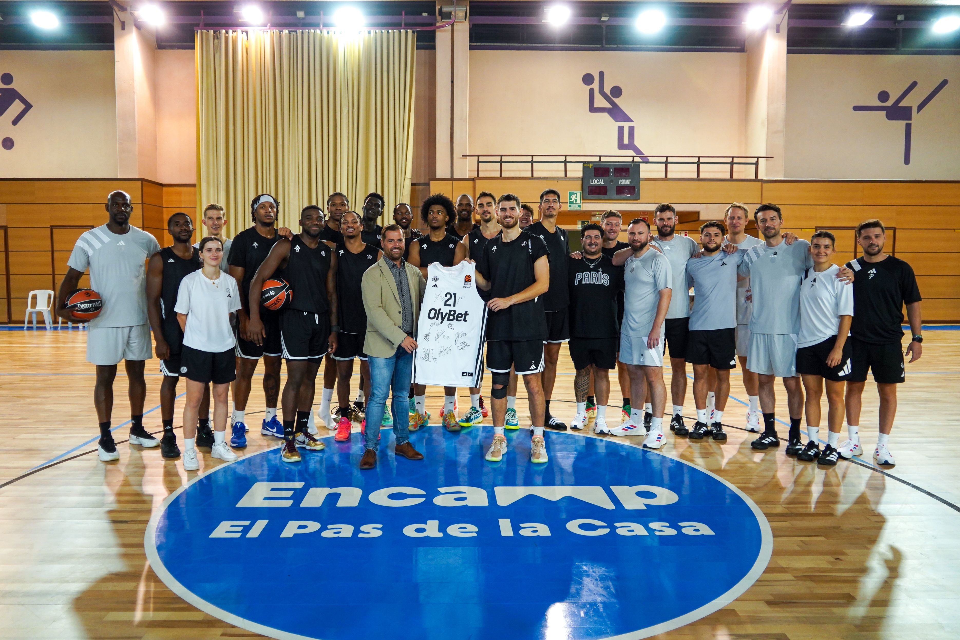 Tot el grup del Paris Basketball entregant una samarreta firmada al conseller Nino Marot al centre esportiu del Pas de la Casa.
