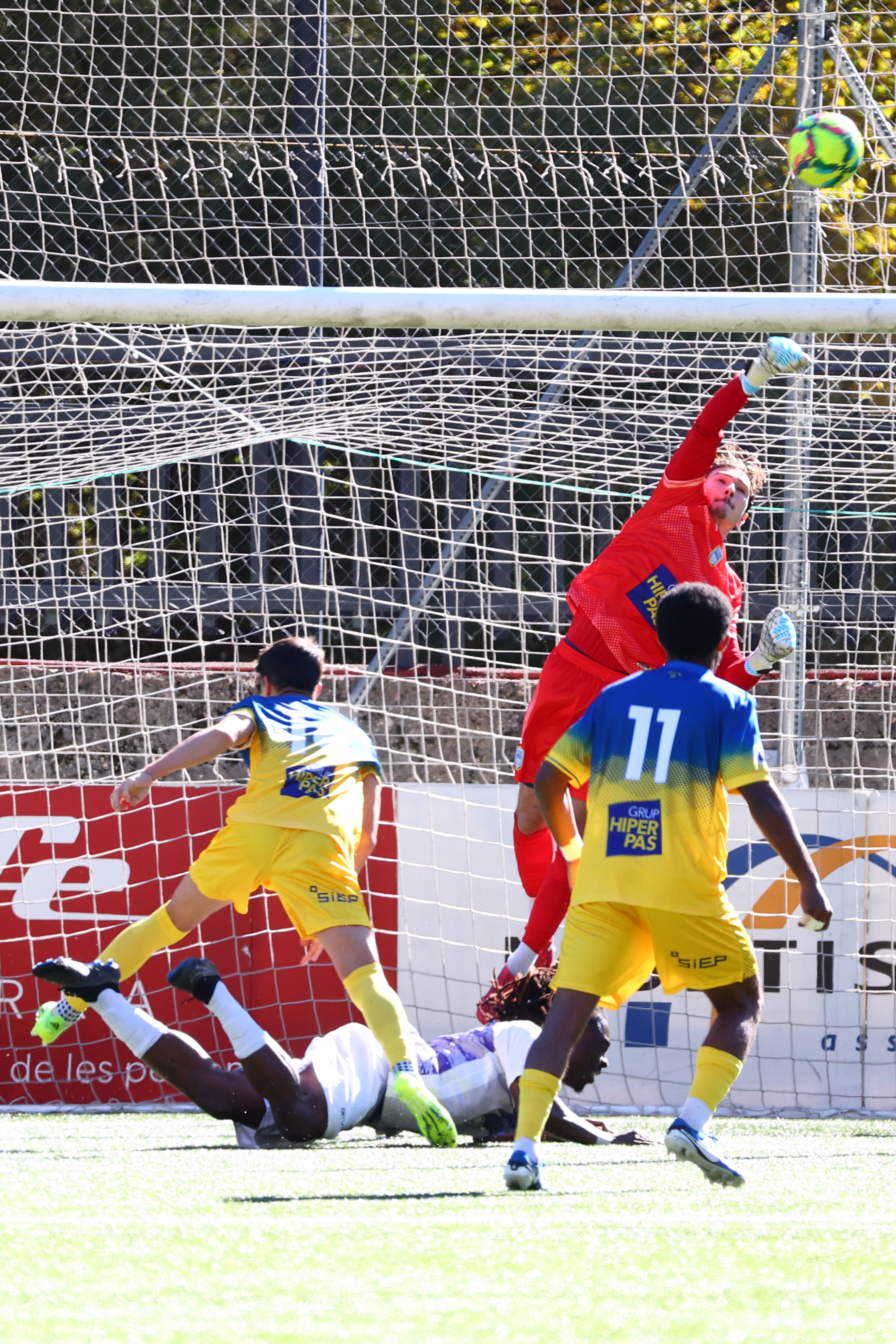 Jugadors del Pas de la Casa, de groc, mirant de solucionar una jugada defensiva.