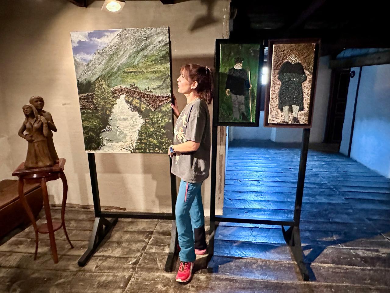 Alba Puig al costat d'algunes de les obres exposades de la seva mare, entre els quals un quadre icònic, el del pont de la Margineda. Alba Puig al costat d'algunes de les obres exposades de la seva mare, entre els quals un quadre icònic, el del pont de la Margineda.