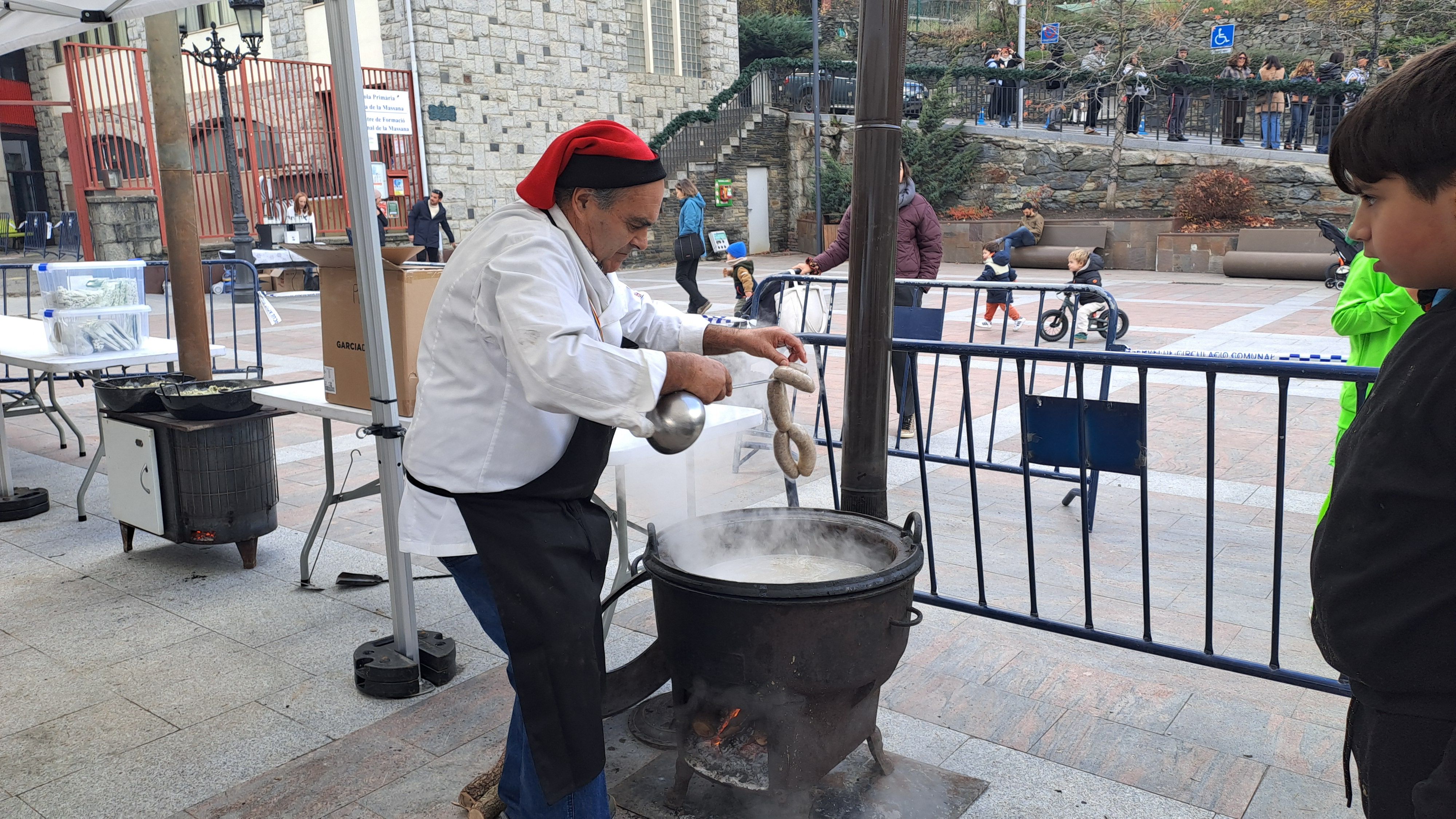 Un cuiner treu les botifarres de l'olla.
