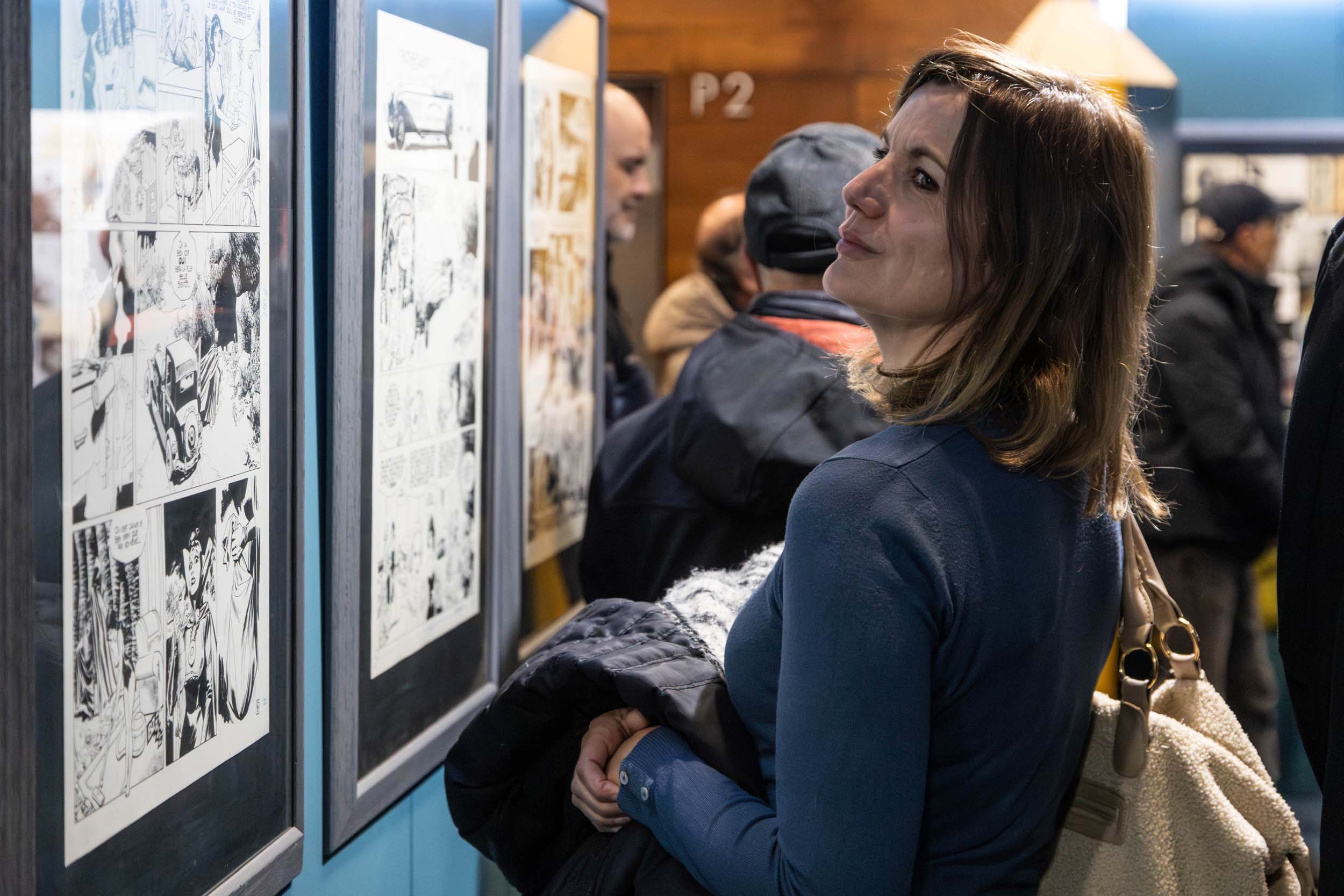 Una dona contempla algunes de les vinyetes exposades. Una dona contempla algunes de les vinyetes exposades.