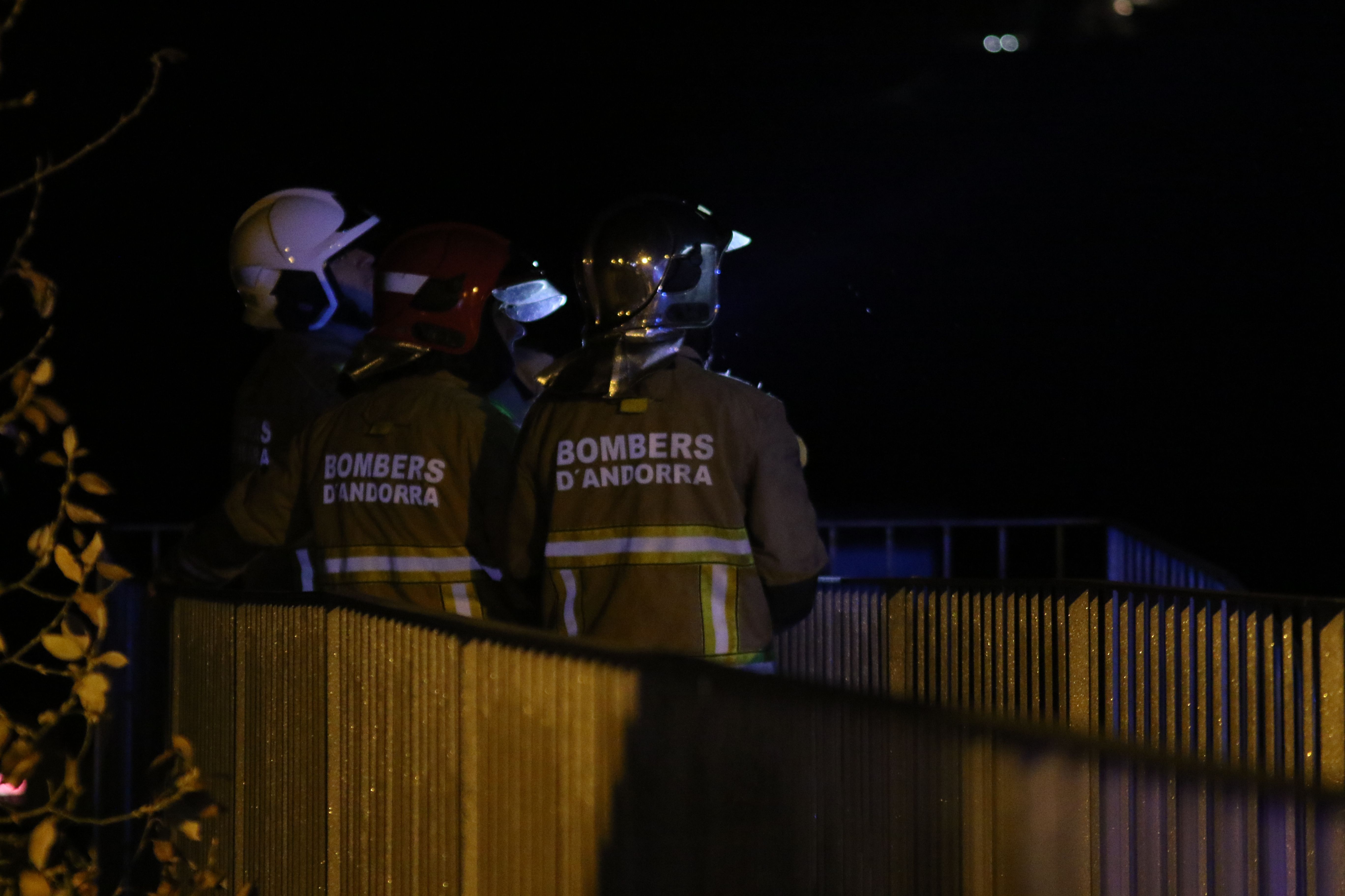 Tres dels bombers mirant l'actuació de companys seus i guiant-los i il·luminant-los.