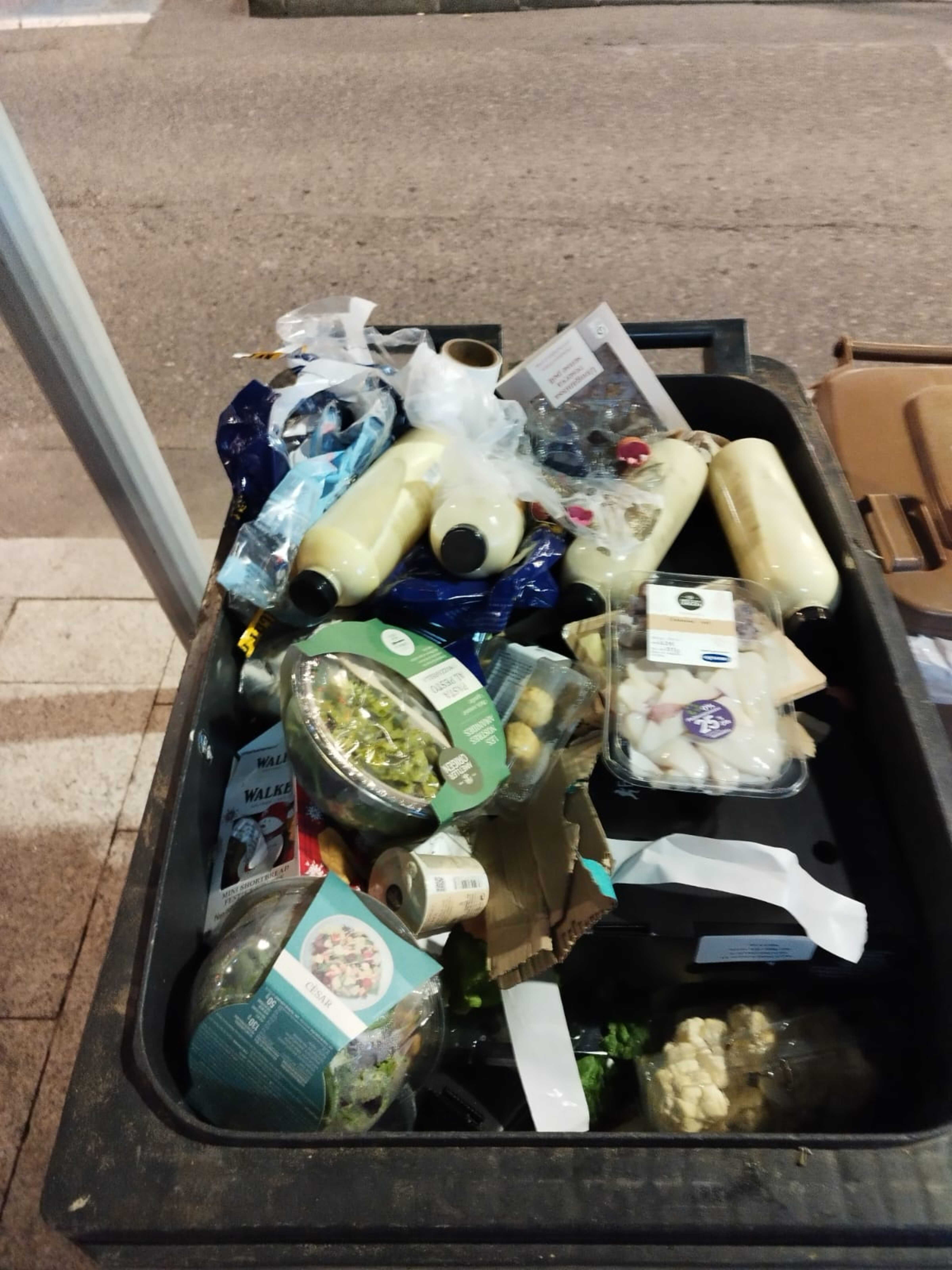 El contenidor ple de safates de menjar llançat.